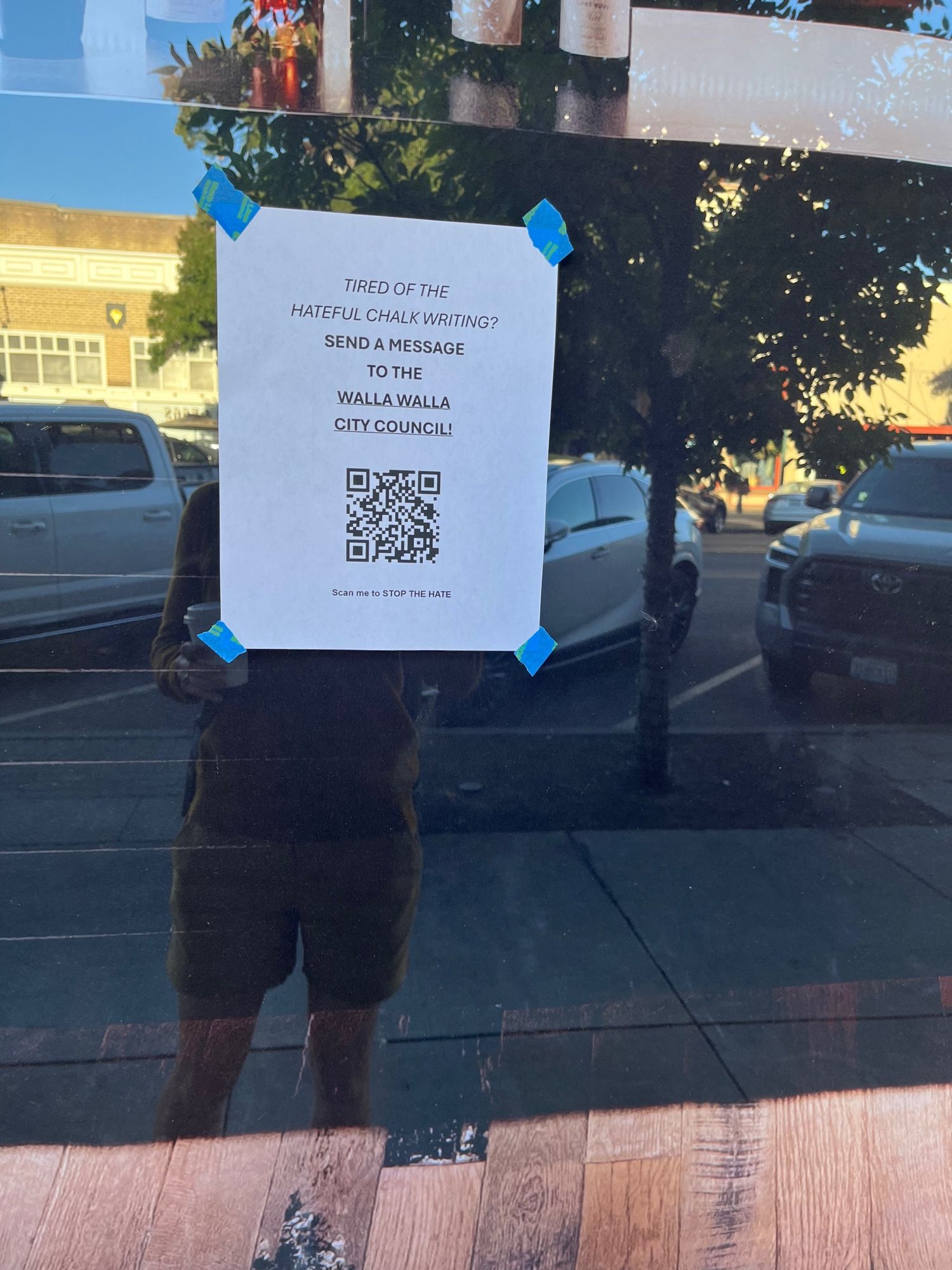 Flyer in window of downtown building with a QR code, reading “tired of the hateful chalk writing? Send a message to the Walla Walla City Council!”