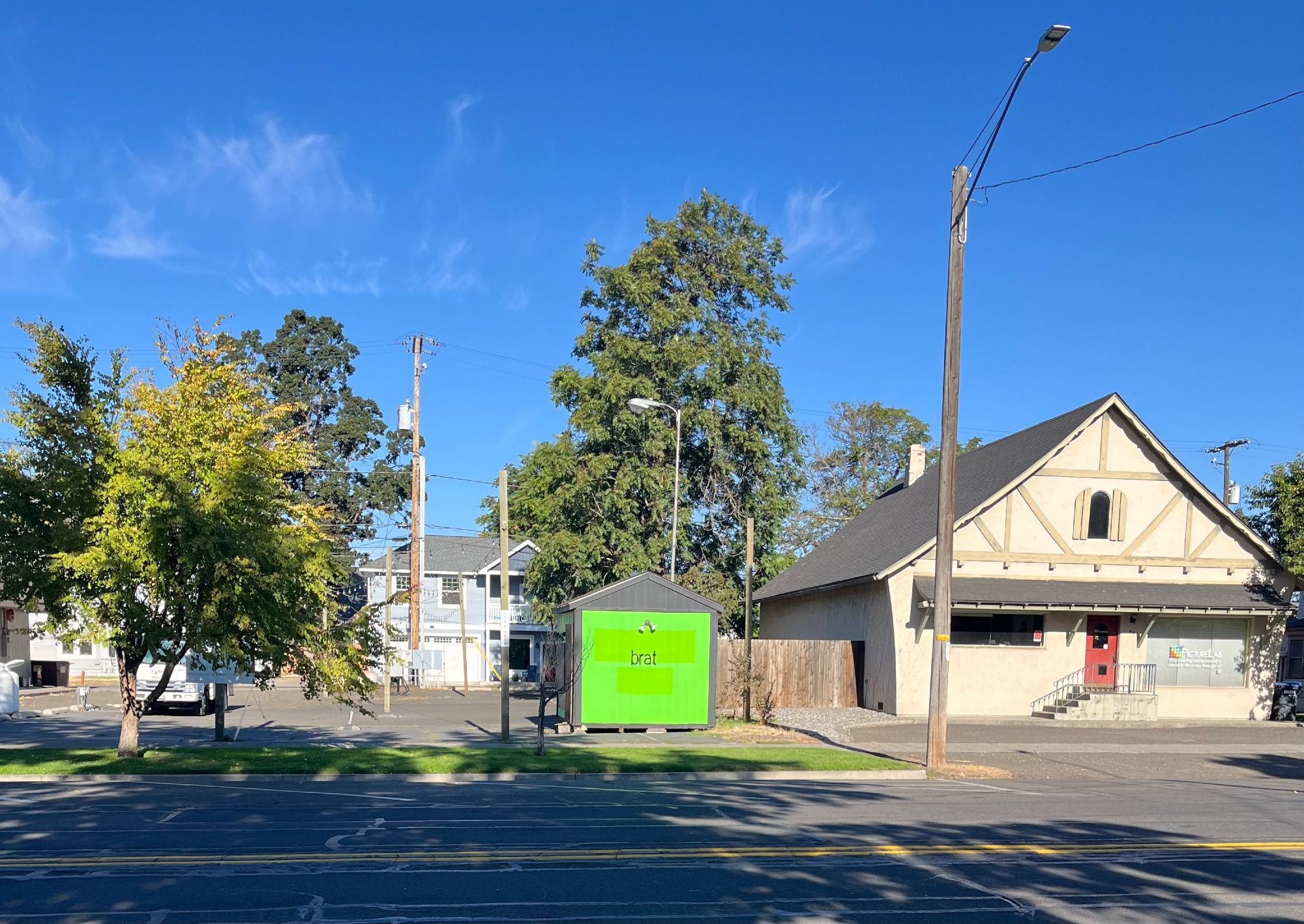 The side of a shed painted neon green with the word “brat” stenciled on it