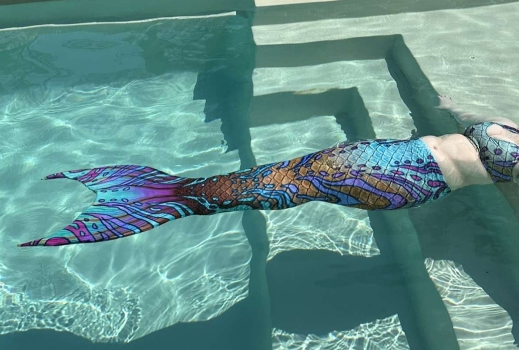 Me floating on my back in a pool, wearing a mermaid tail