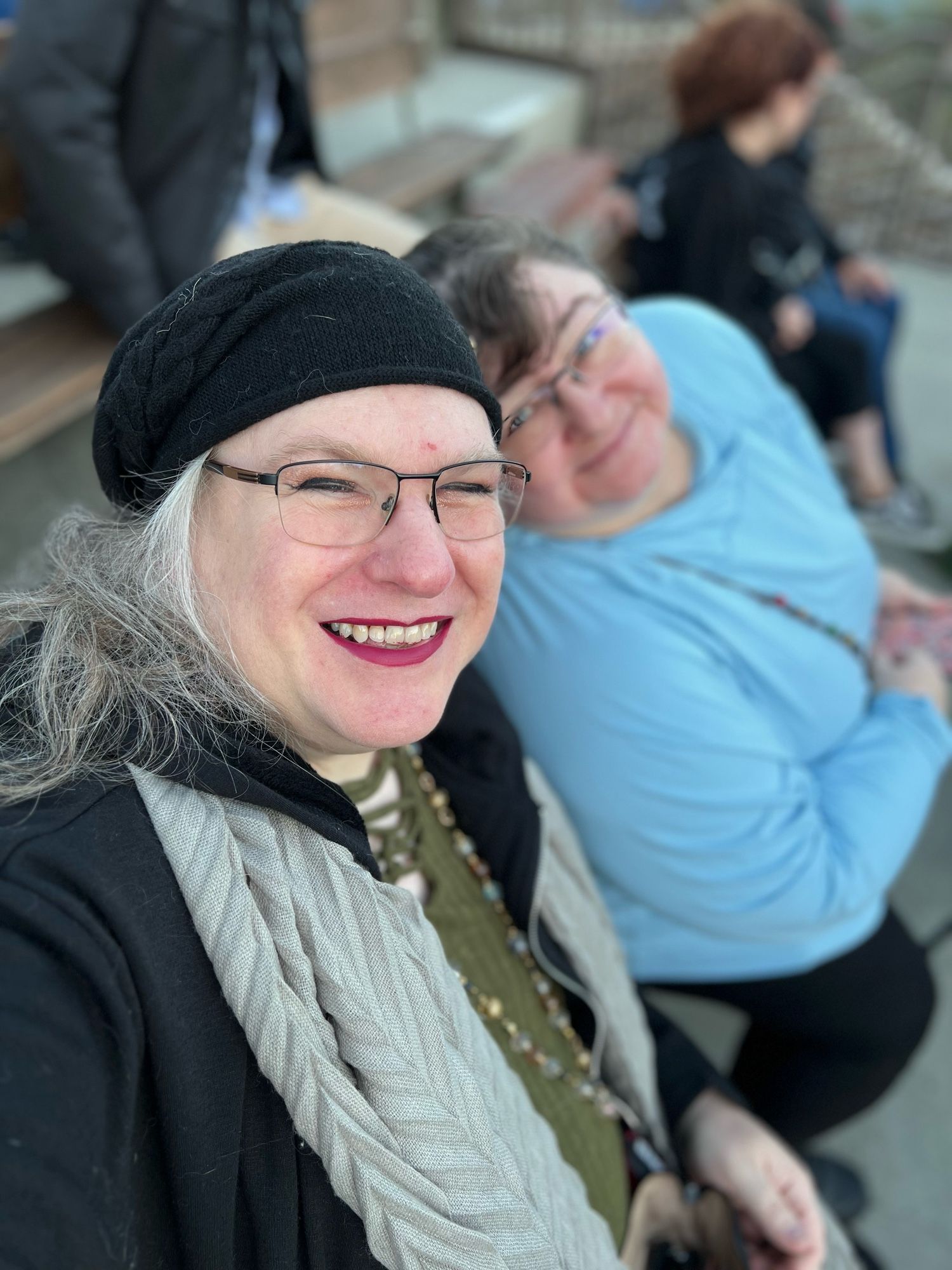 trixie in an amphitheater with her wife, fredlet, on the other side of her, leaning into frame