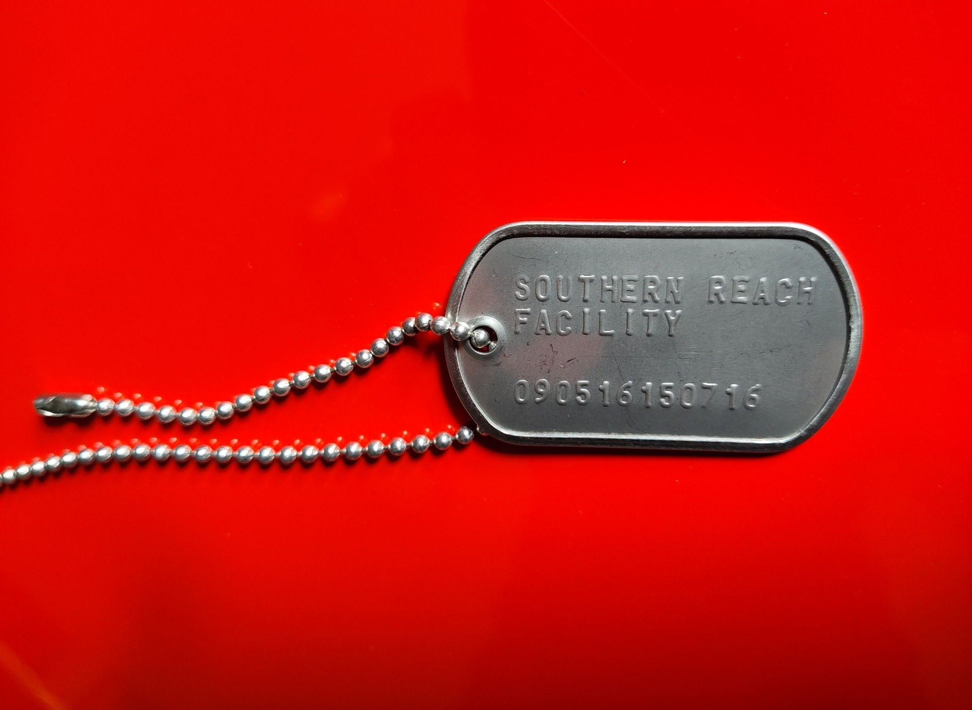 dogtag with Southern Reach  Facility on it, against red backdrop.