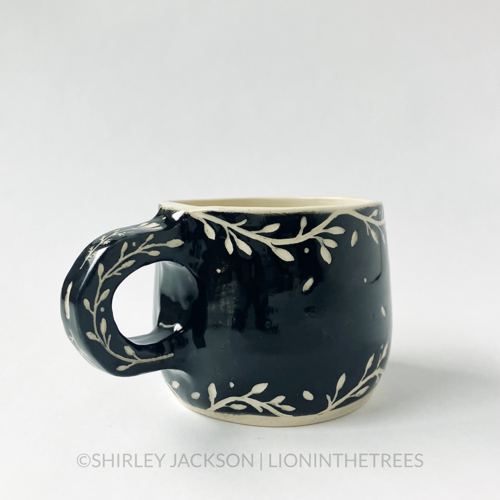 Ceramic black sgraffito mug featuring my Running Fox motif. This mug also features a floral border above and below the fox motif.