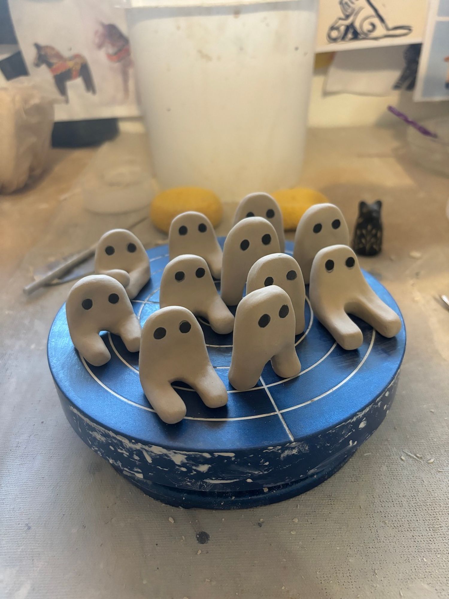 A group of small, ceramic, Fresno Nightcrawler sculptures.
Some are sitting down and some are standing.