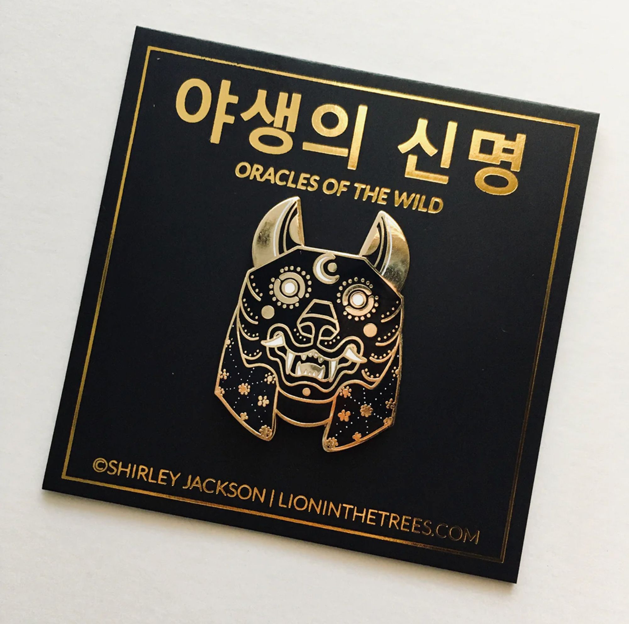 Oracles of the Wild The Lunar enamel pin. A black, gold, and white enamel pin designed to look like a wolf mask.