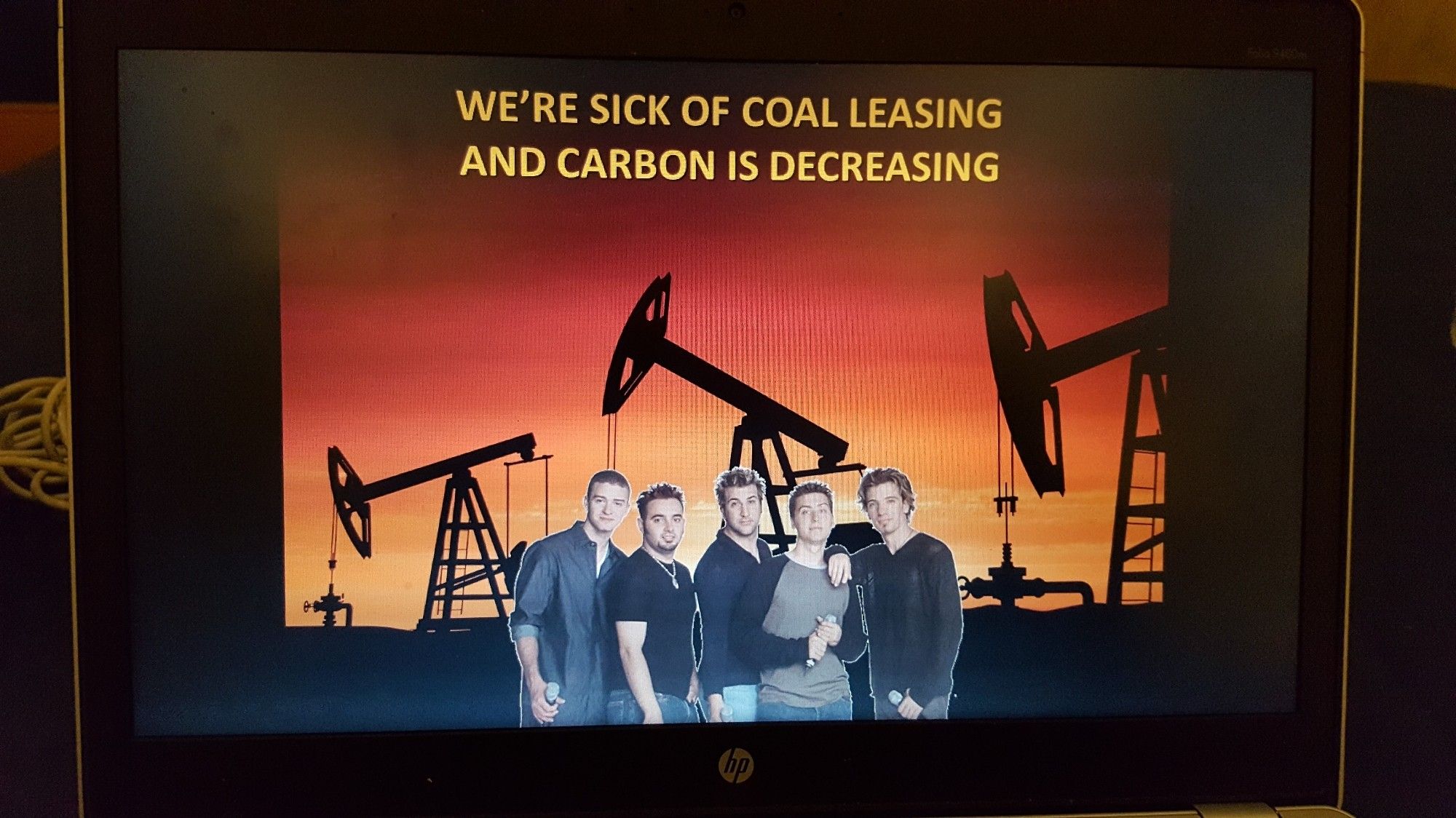 The members of NSYNC pose in front of fossil fuel extraction infrastructure with the lyrics "we're sick of coal leasing and carbon is decreasing"