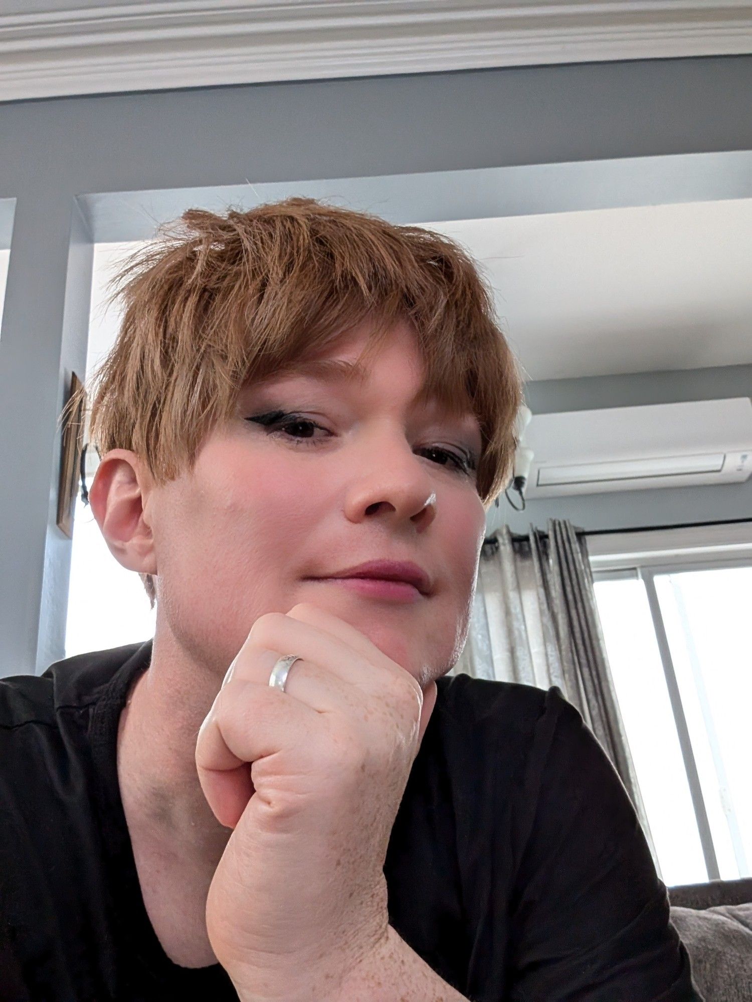 Picture of the account holder. Ginger pixie cut light makeup, eyeliner looking at the camera.