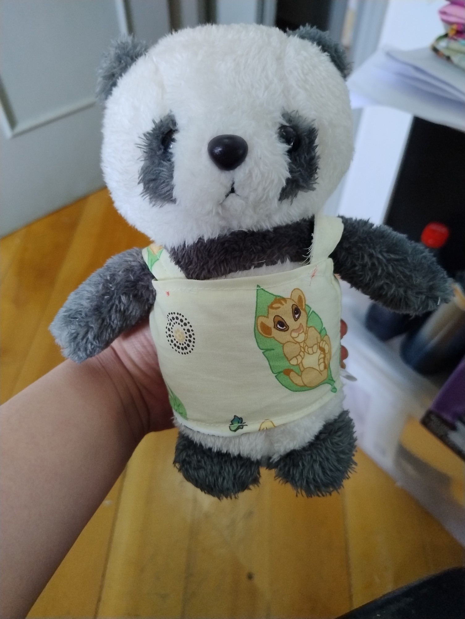 a photo of a panda plush wearing a crudely sew together shirt