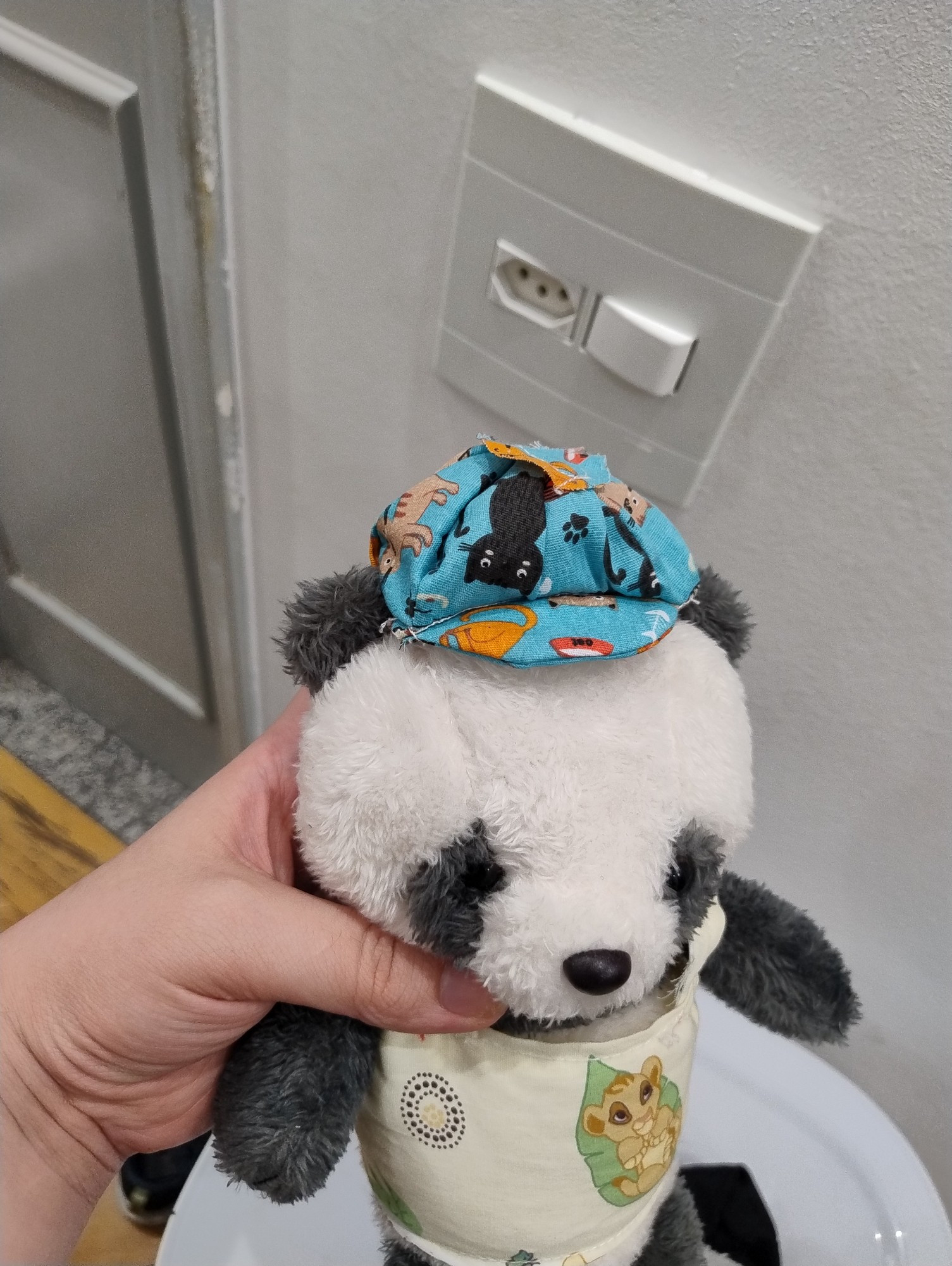 a photo of a panda plush wearing a crudely sew together shirt and little hat