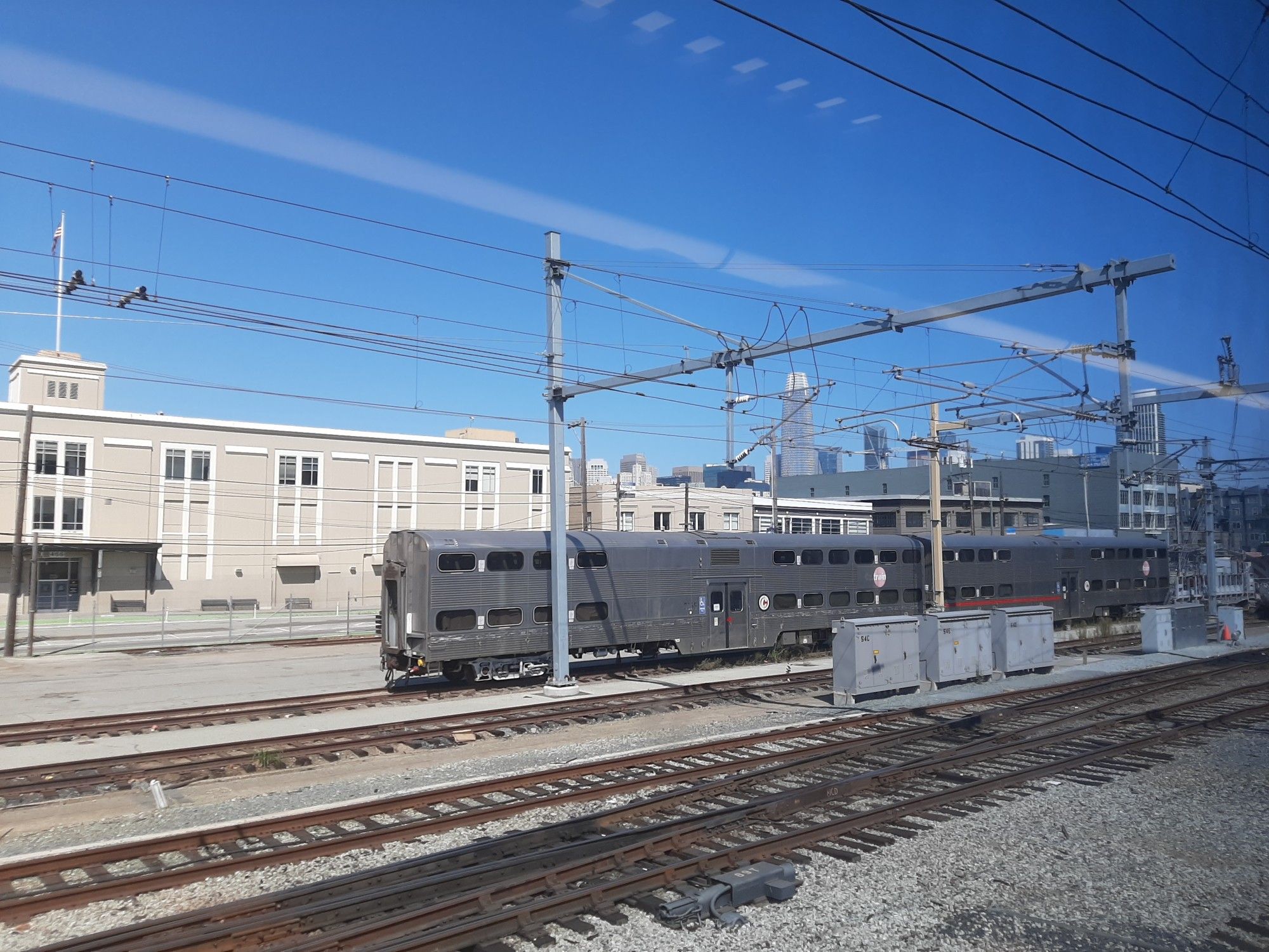 One of Caltrain's old diesel trains at the San Francisco train station, with the city skyline in the background.