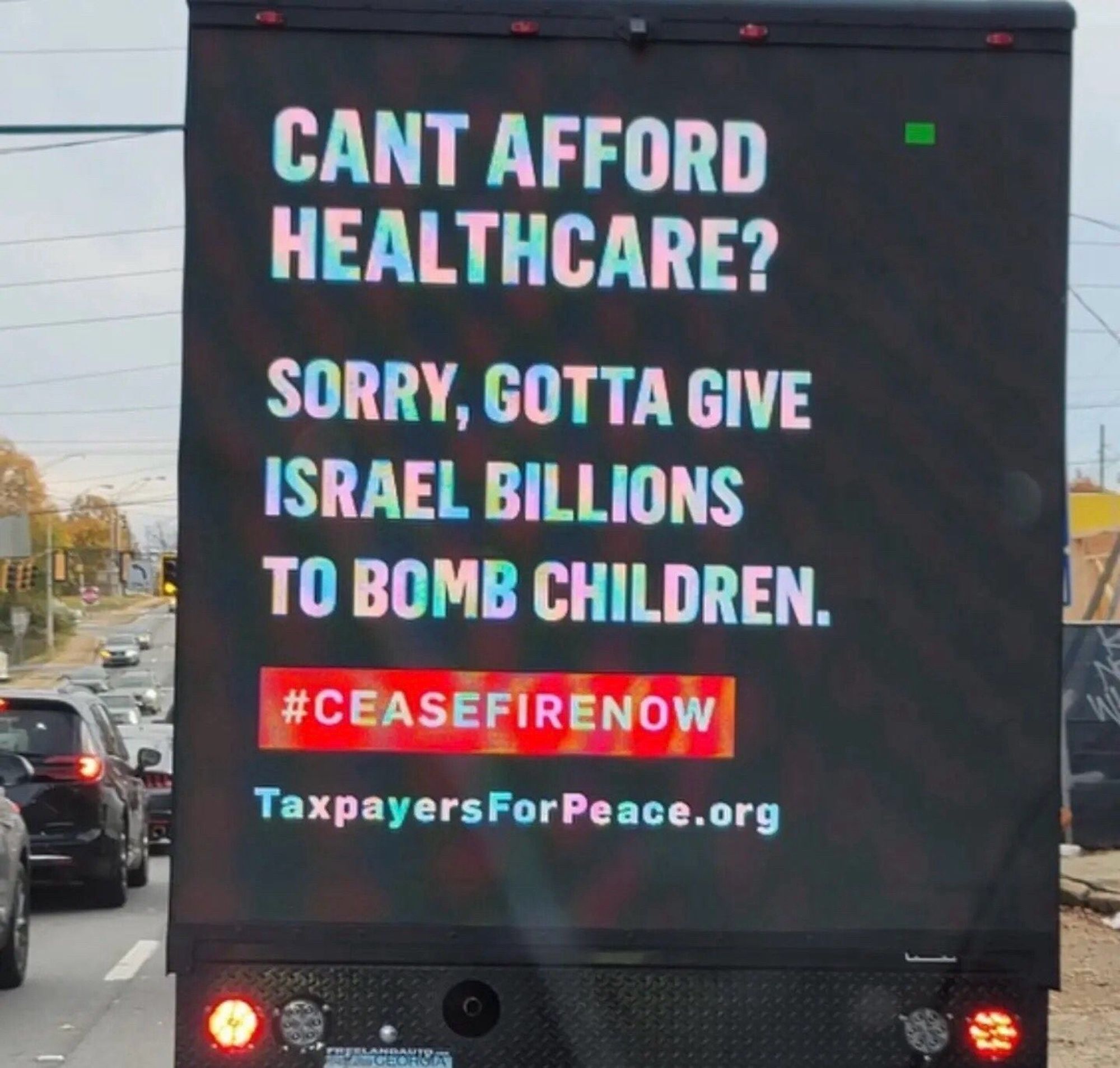 Back of a truck with the text “can’t afford healthcare? Sorry, gotta give Israel billions to bomb children. #ceasefirenow by taxpayersforpeace.com”