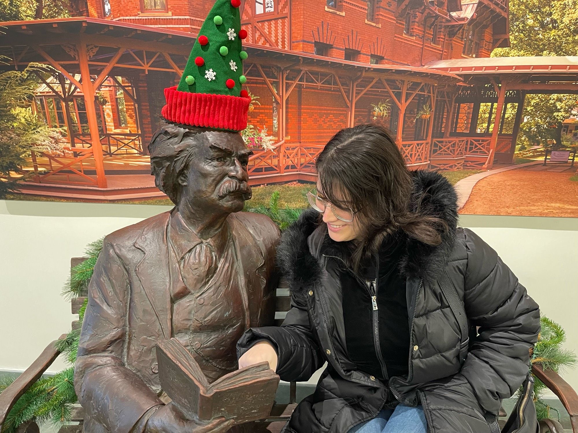 Sitting next to a bronze Mark Twain, holding a book, with yours truly pointing to something inside the book