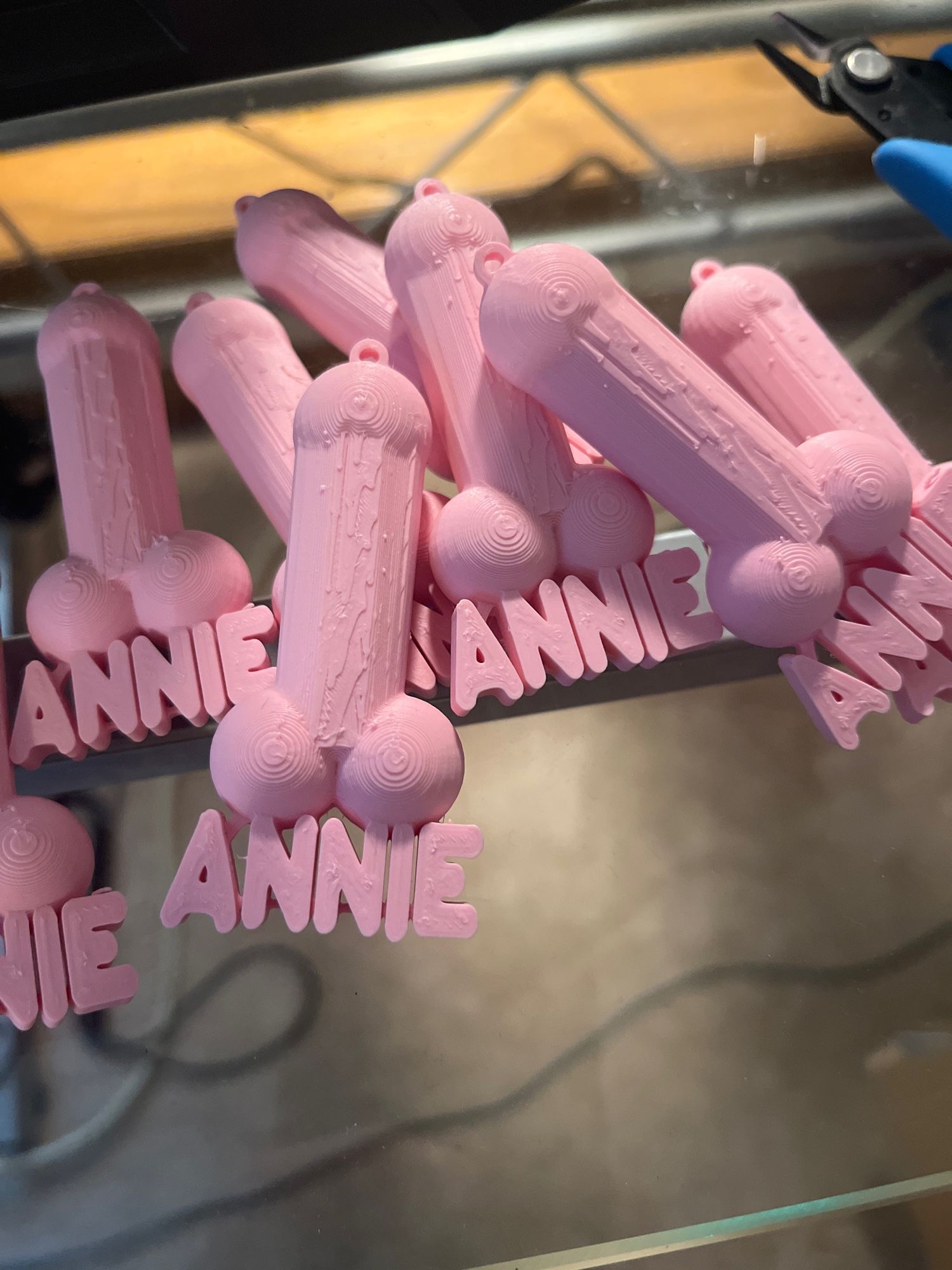 Photo of 3D printed pink necklace pendants shaped like penises with the name Annie at the bottom of each pendant.