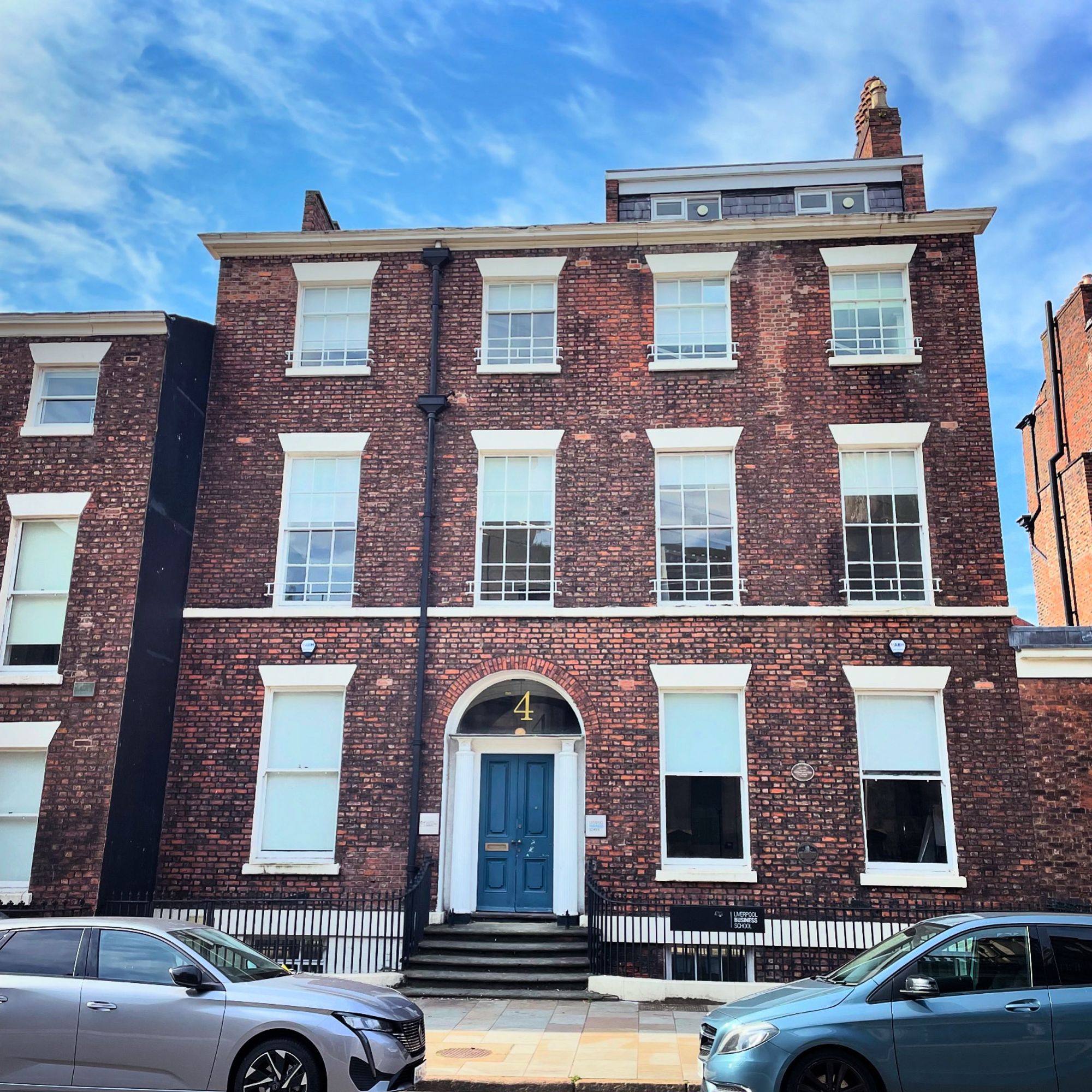 A brick building in Liverpool. Three stories with a small roof extension. The front door is blue underneath a fan-light with a large number 4 painted on.