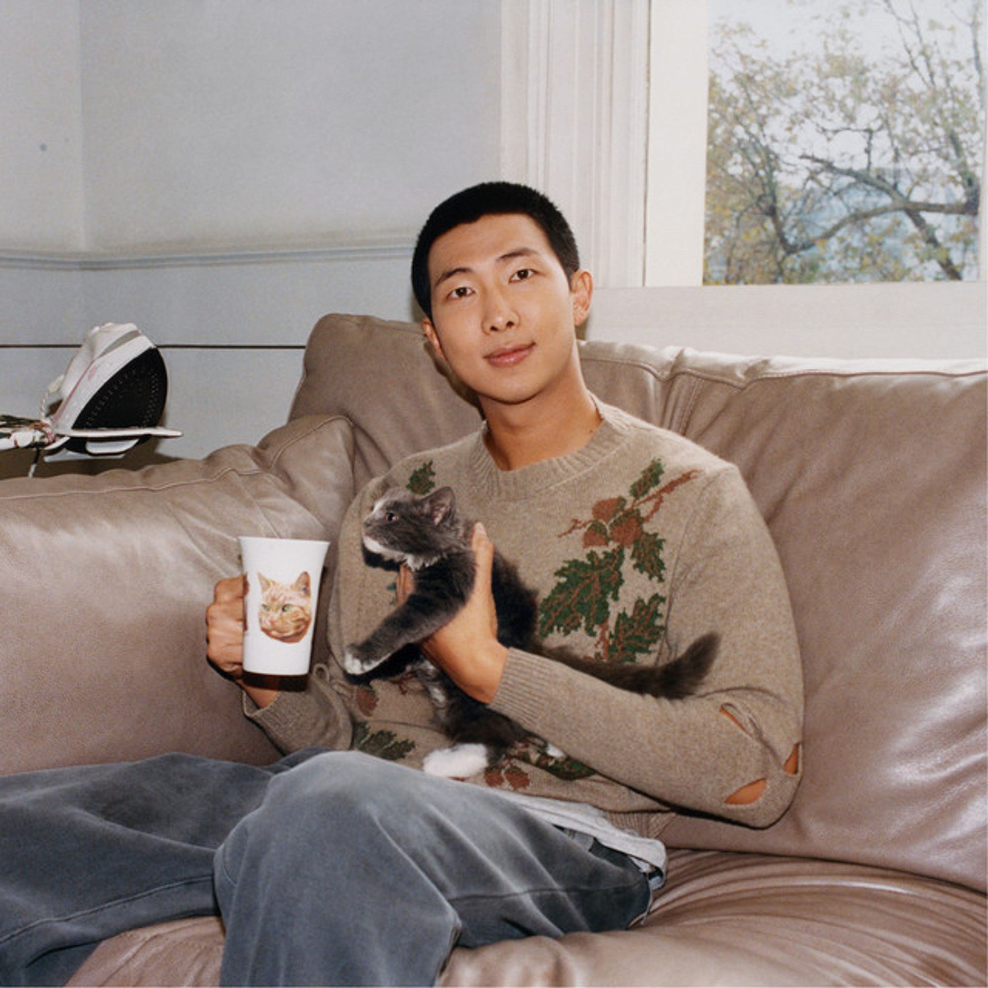 Namjoon holding a kitten with a mug w/a  kitten on it, in a leaf decorated sweater