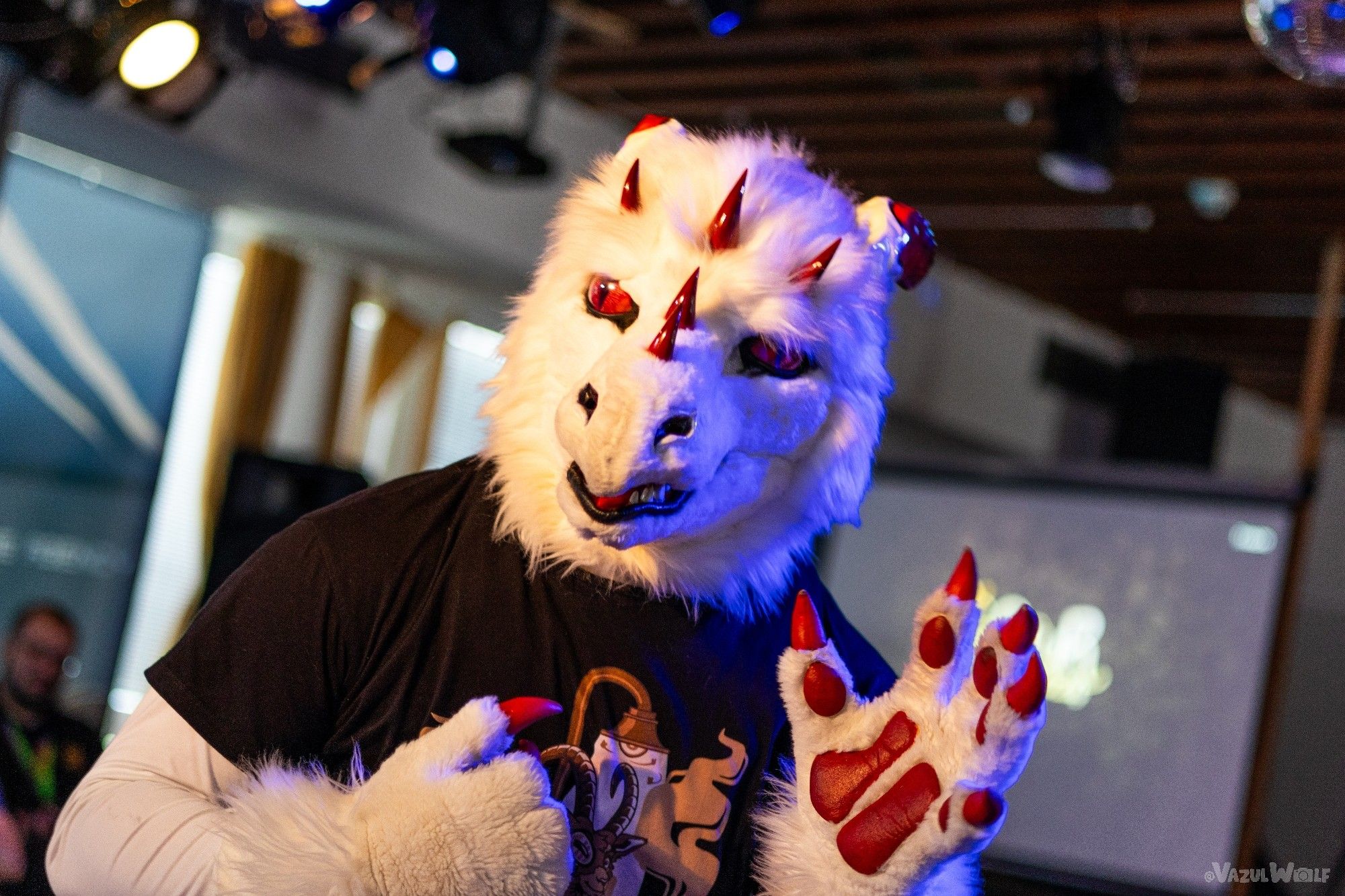 White dragon costume, with red horns and claws, raising his hand looking off into the distance.