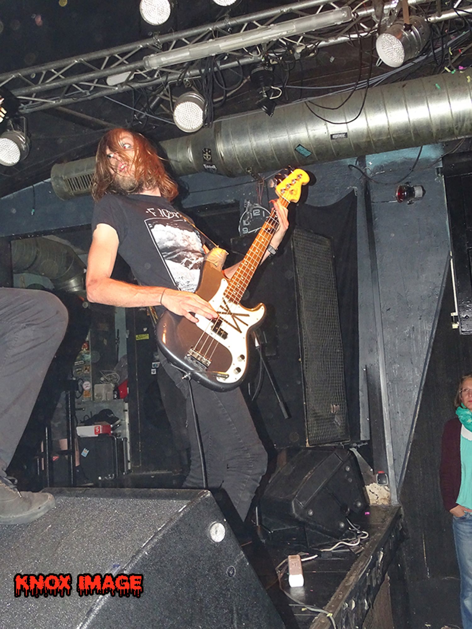 punk bassist mit langen haaren auf bühne schaut zur seite