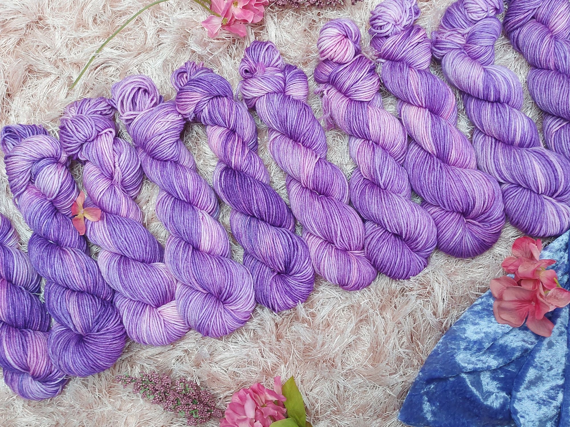 Purple and pink yarn, adorned with pink flowers and blue velvet cloth.