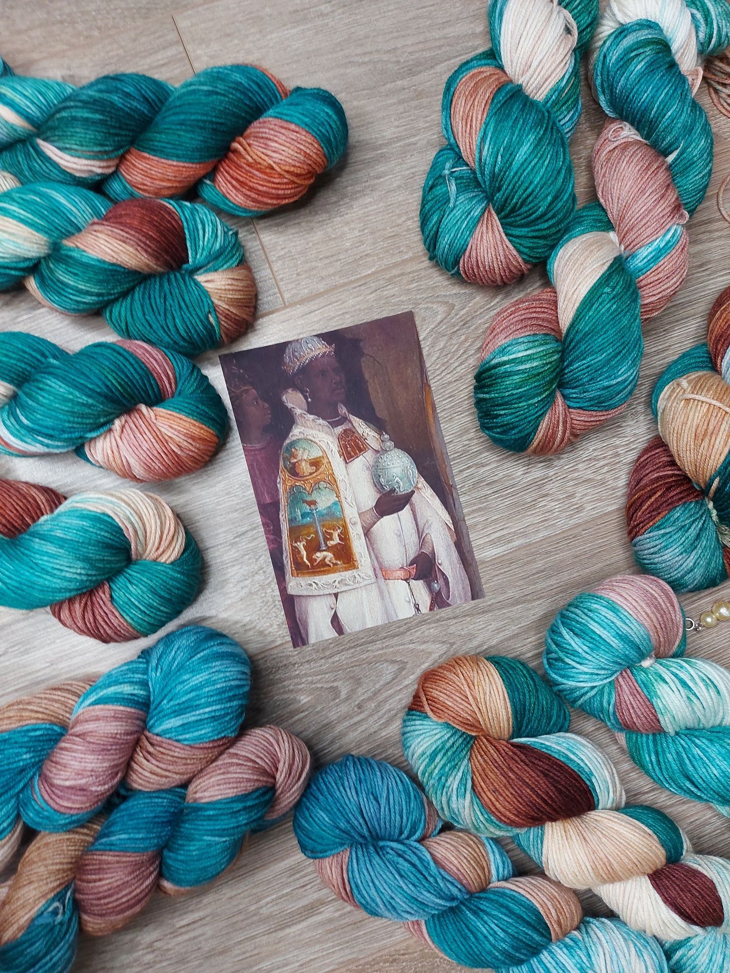 Teal and brown skeins of yarn, adorned with a photo of a magus dressed in the same colors.