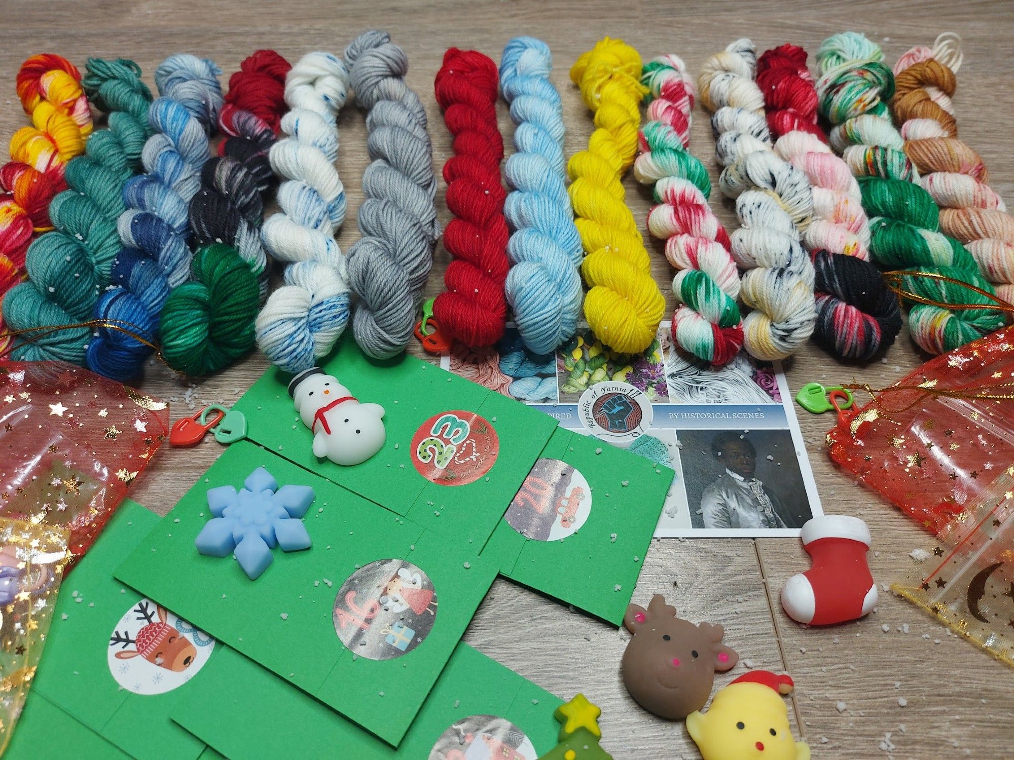 A row of miniskeins, a postcard, christmas bags and little ornaments in a picture.