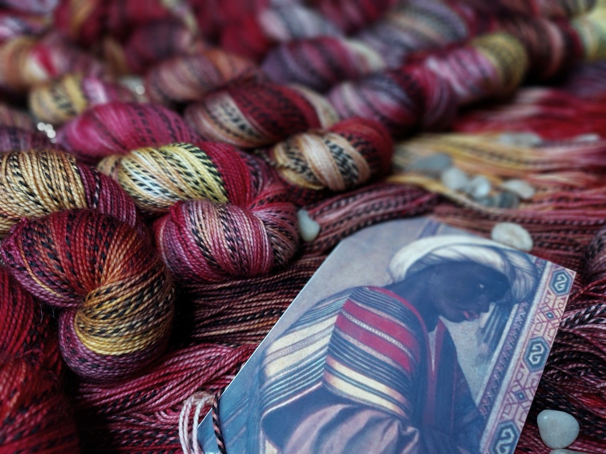 Red, gold, and black zebra pattern yarn, adorned with decorative stones. A photo of a Black servant dressed in the same colors is in the shot.