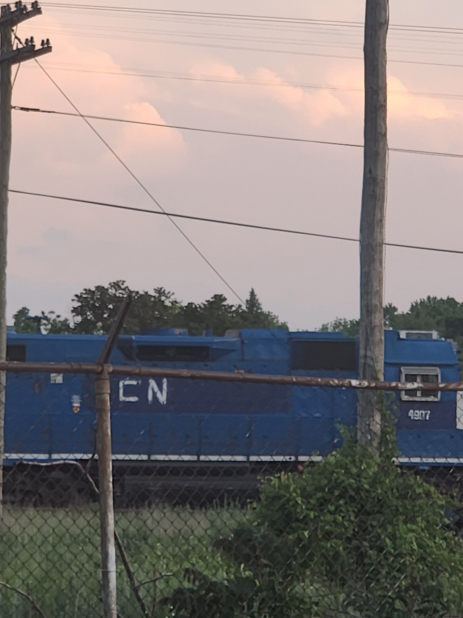 A blue train engine that has its original company's name/logo painted over with a different shade of blue and a hastily spraypainted CN in white over it