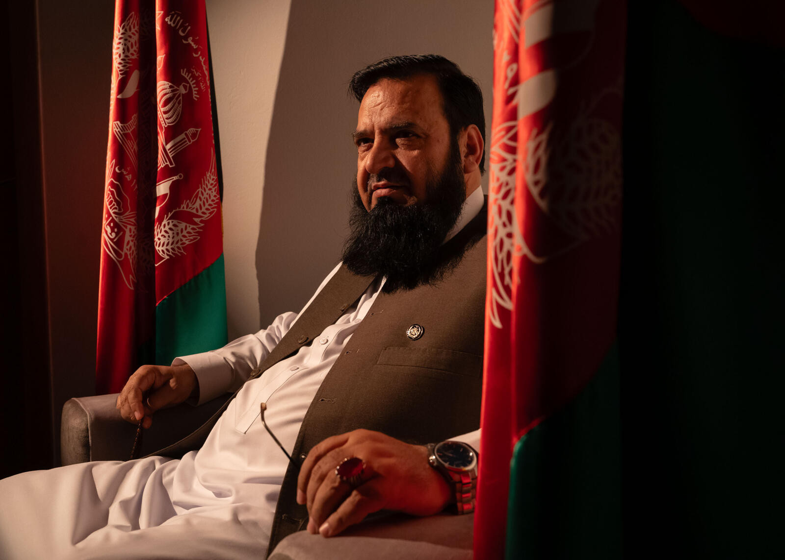Photo of 53-year-old Afghan scholar Mohammad Halimi. He is sitting, wearing white pants and shirt with a brown vest.