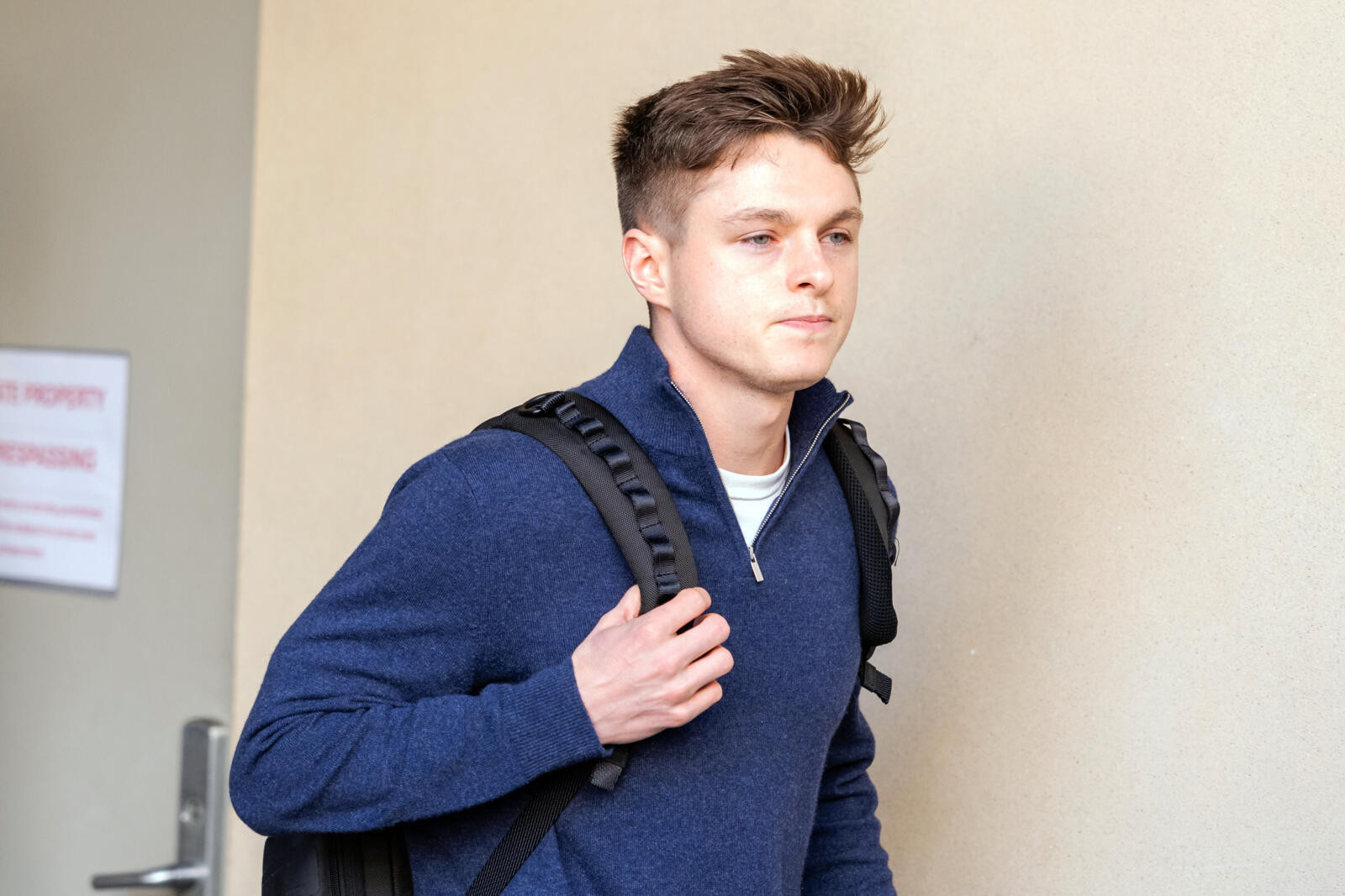 Photo of DOGE staffer Nate Cavanagh, a 28-year-old white man in a blue pullover, carrying a black backpack.
