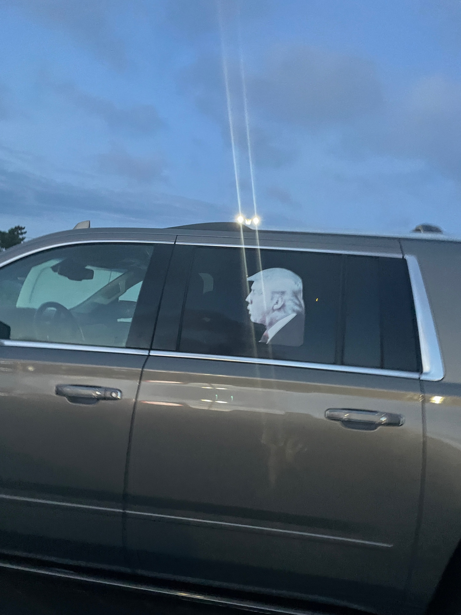 A car decal on the back seat of a big suv of Trump blowing a kiss or something. 
