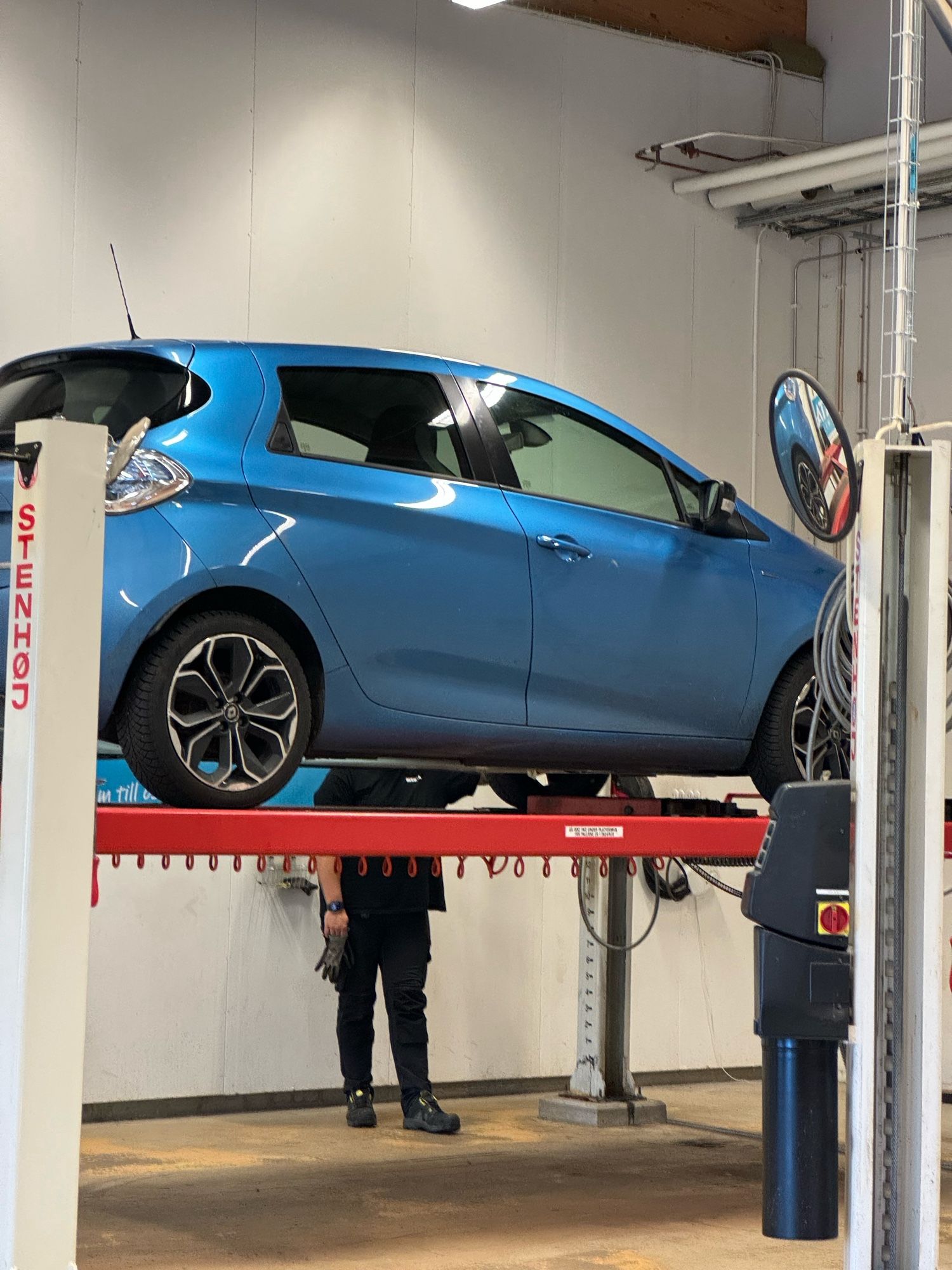 A blue car being lifted up for inspection in a workshop