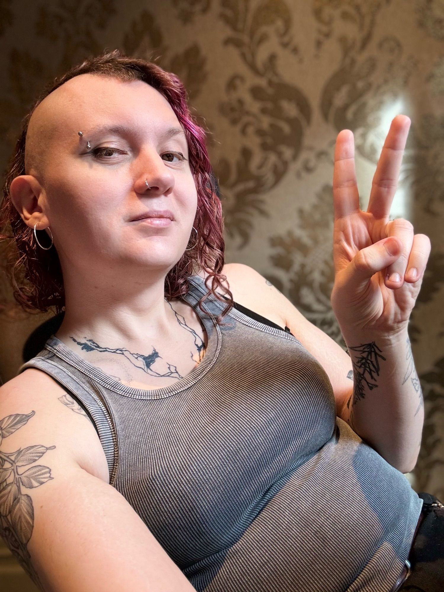 Andrea in a selfie doing a V hand thing, the right side of her head freshly shaved