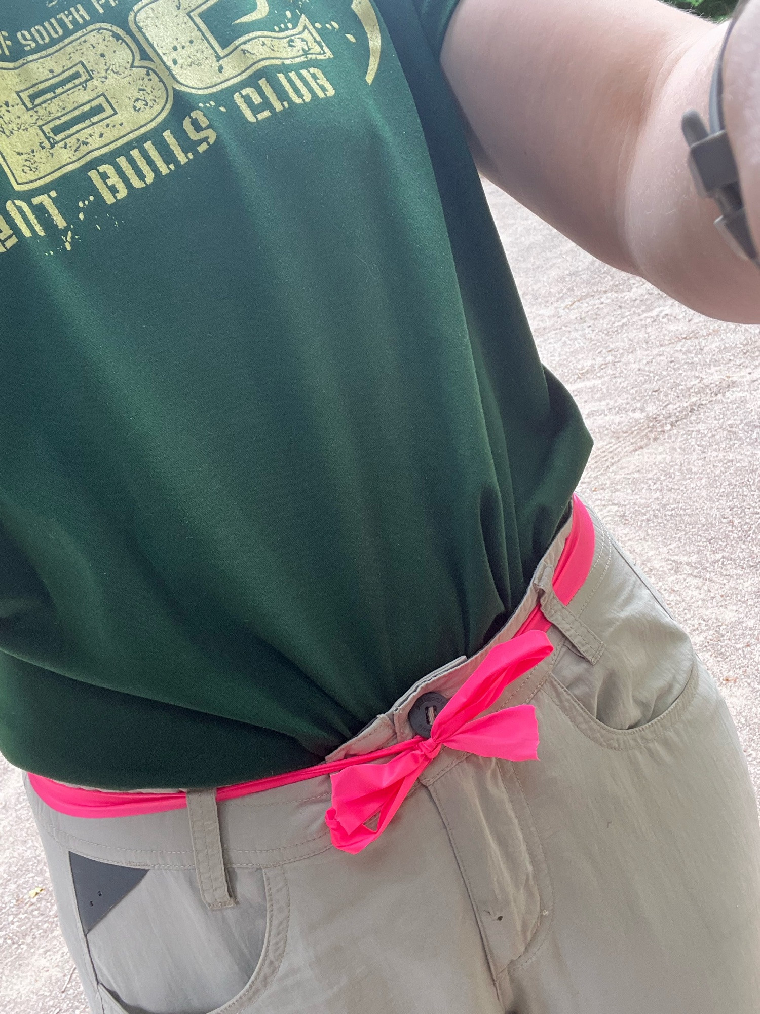 Hiking pants secured with a bright pink flagging tape belt.