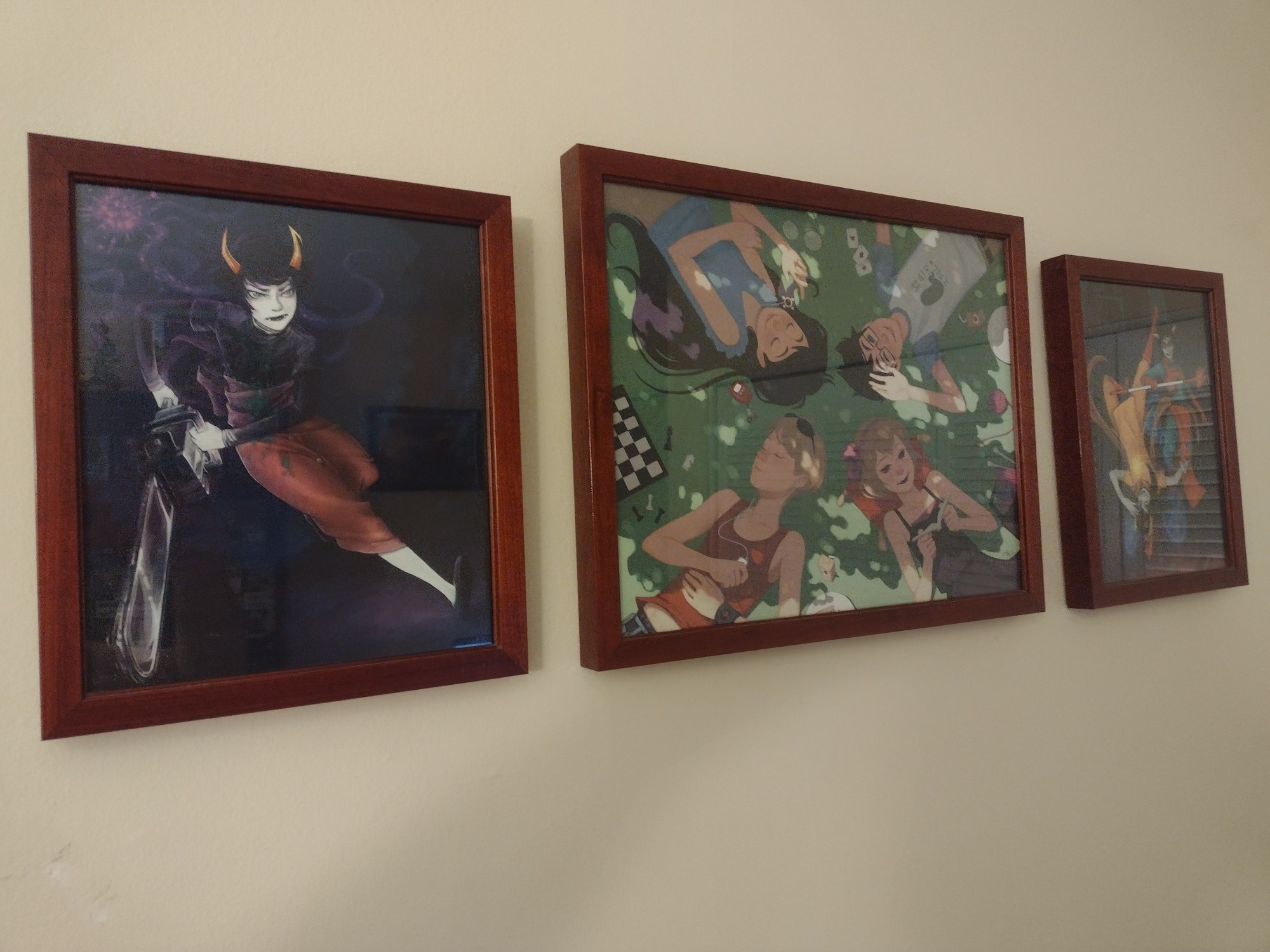 A tastefully angled shot of three framed Homestuck prints depicting Kanaya, the four beta kids, Vriska and Terezi.