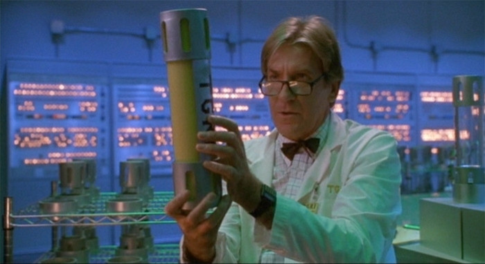 Still from the movie Teenage Mutant Ninja Turtles 2: Secret of the Ooze showing a scientist holding a canister of the titular ooze