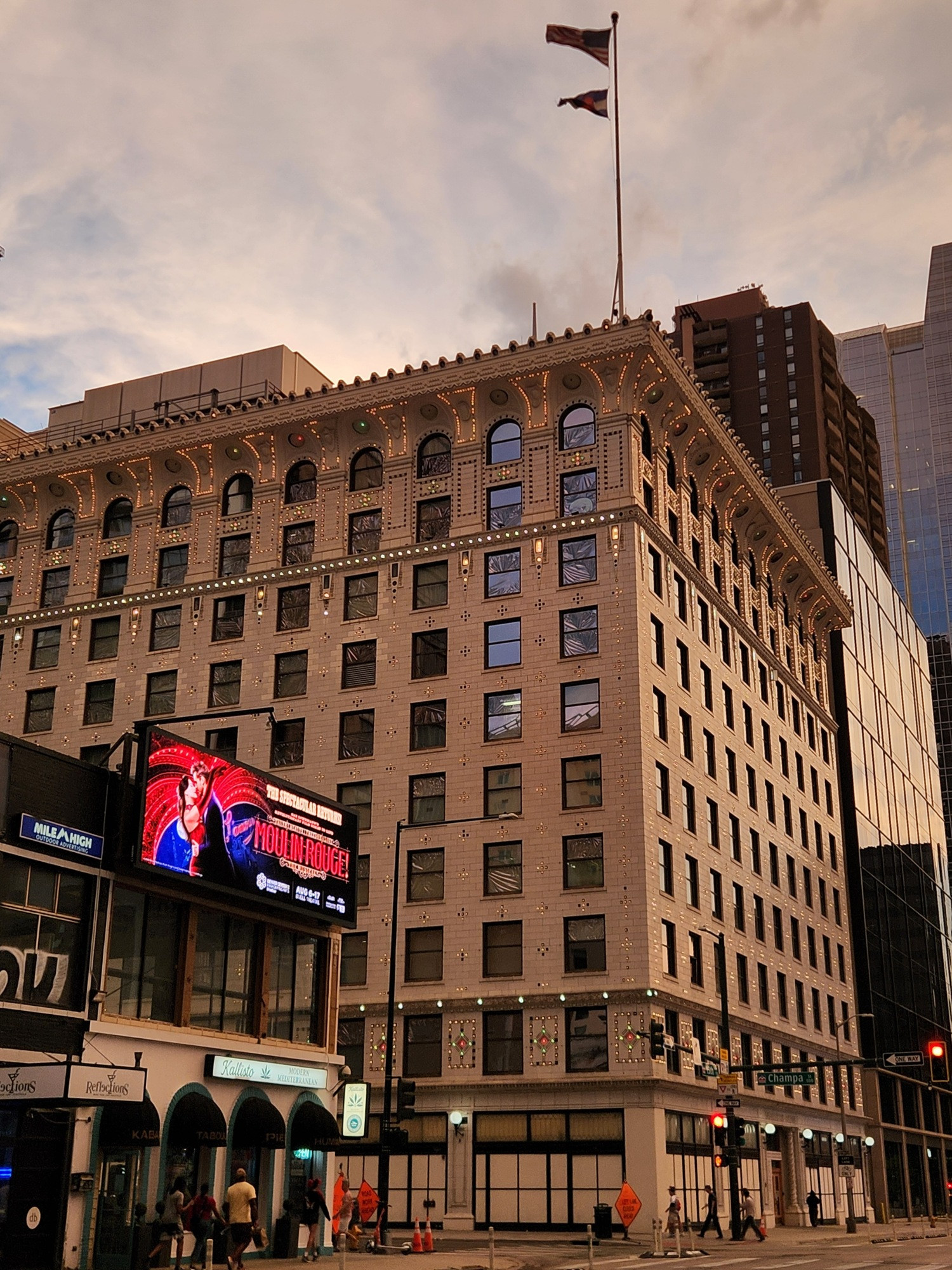 A photo of a ten story early 20th century office building, with a largely smooth stone brick facade broken up by terra cotta ornamentation that is filled in with countless light bulbs, most warm yellow in time but some in different colors.