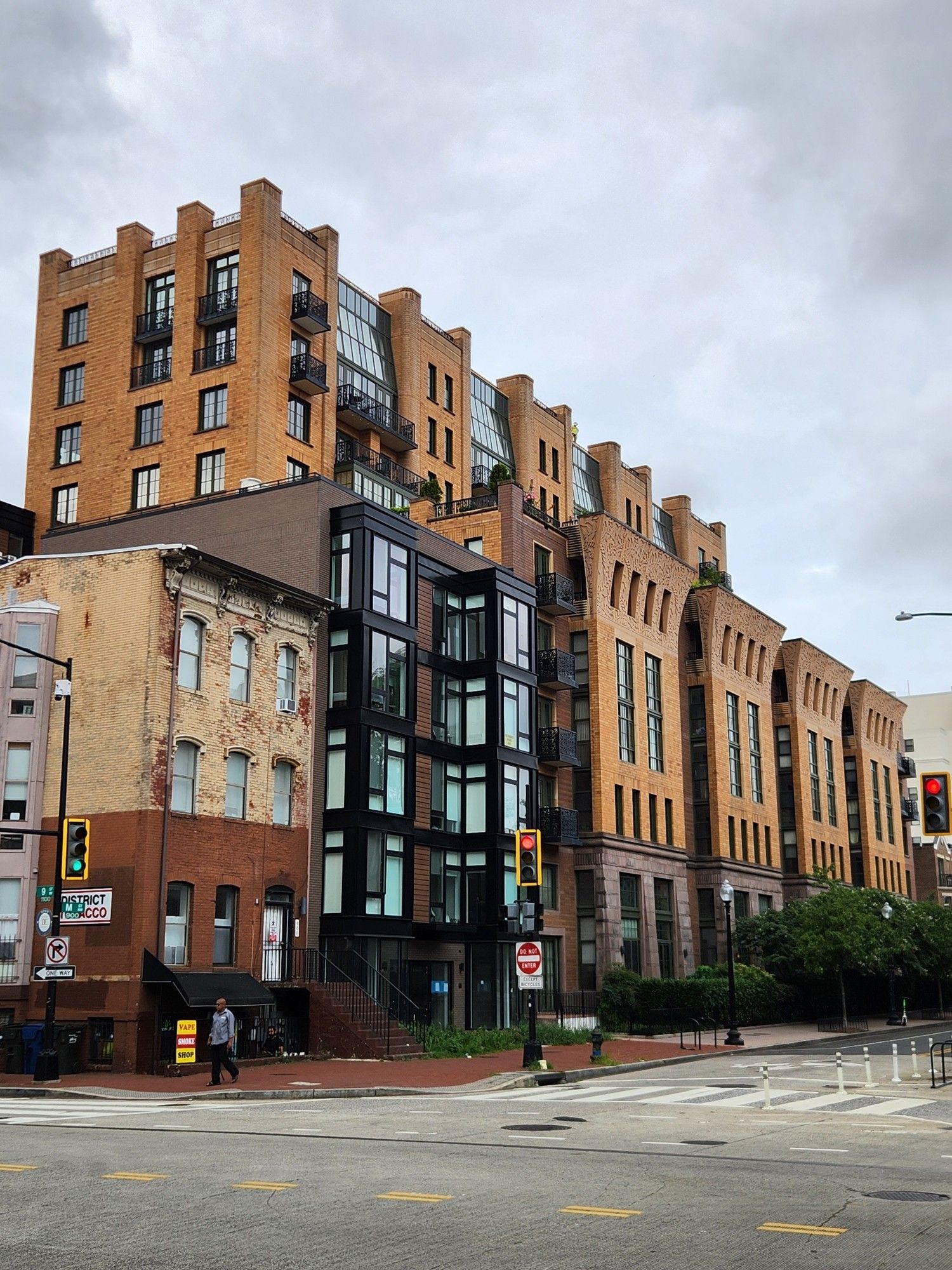 An approximately ten story building with a very ornamented stone and brick facade on the bottom half, and a set-back upper facade terminating in brick columns that stick up past the roof