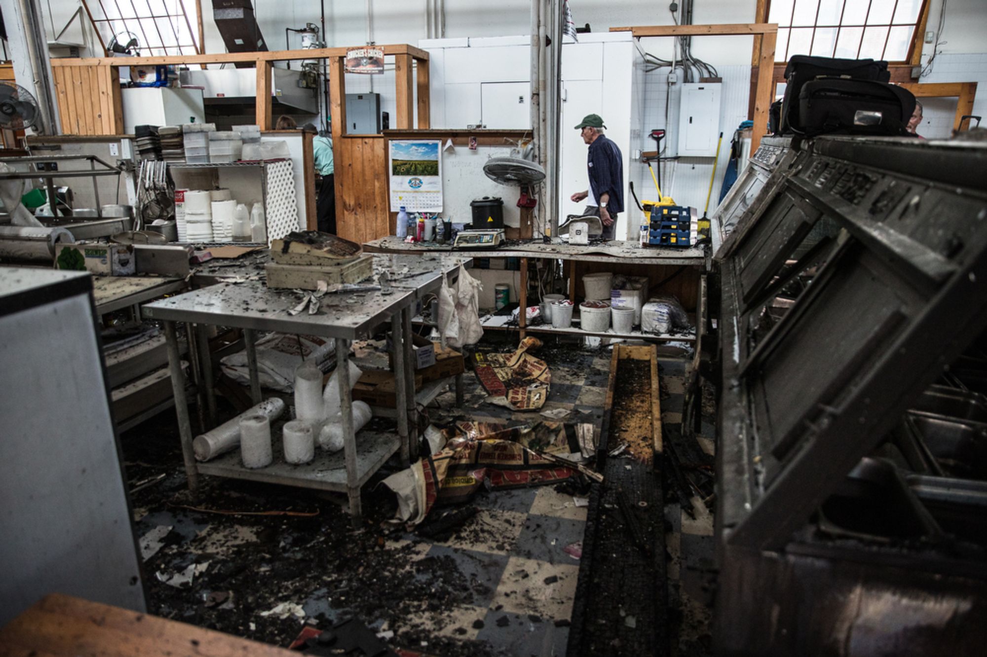 A kitchen setup covered with soot and debris following a fire.