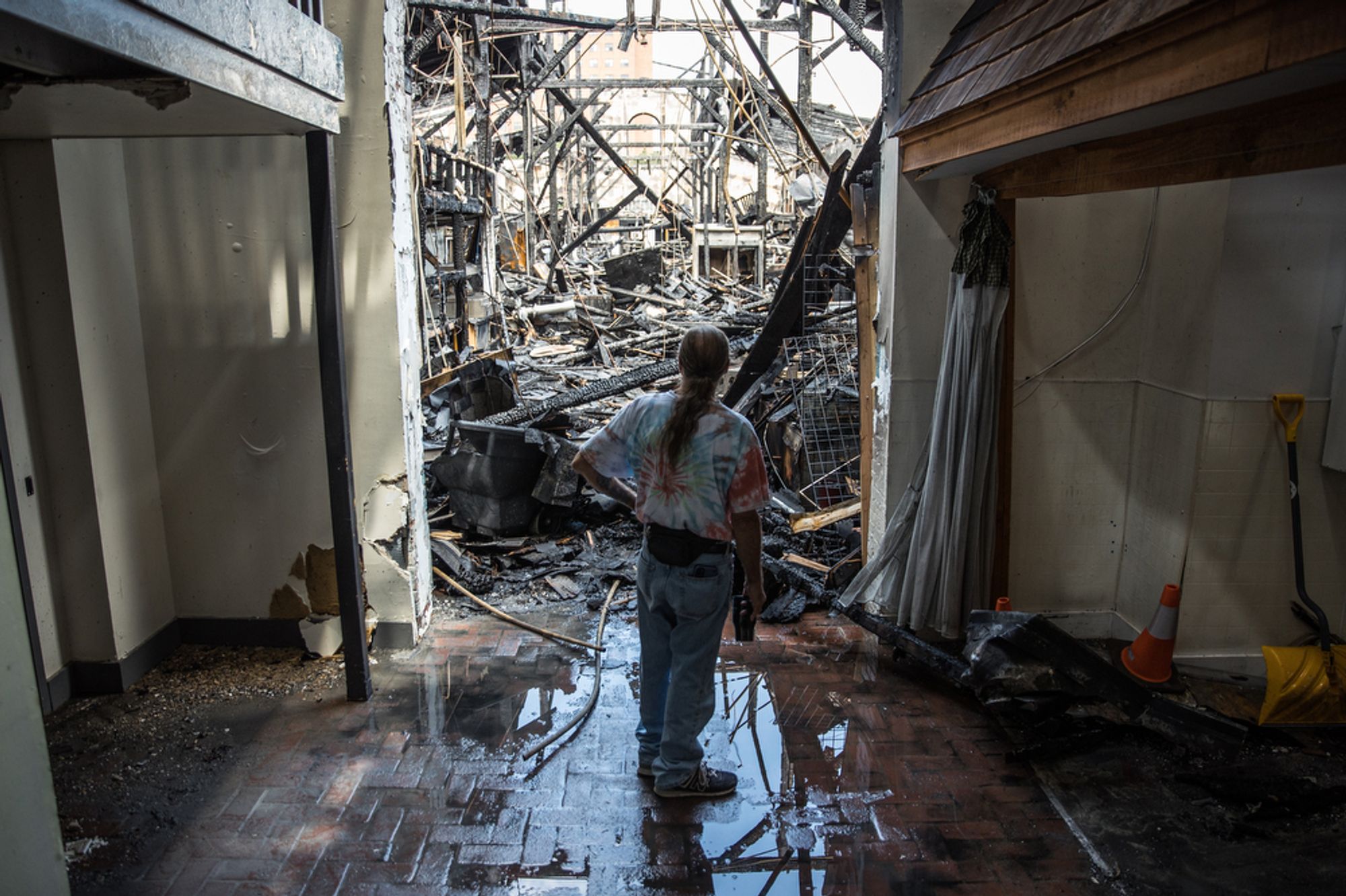 A person looks at debris in a burned-down building.