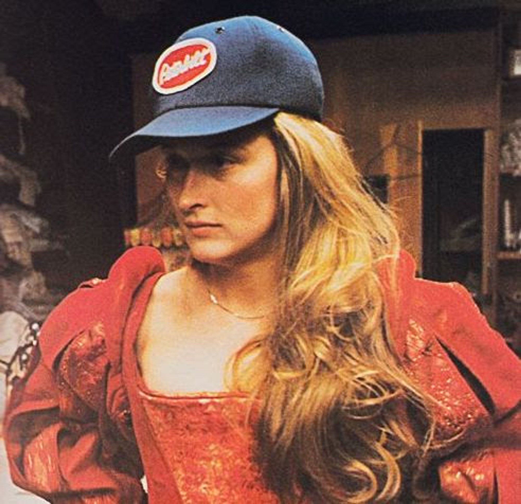 Meryl Streep rehearsing for the Taming of the Shrew August 6, 1978, wearing a period (?) dress in bright red, long blond hair pushed to one side and deep blue Peterbuilt cap