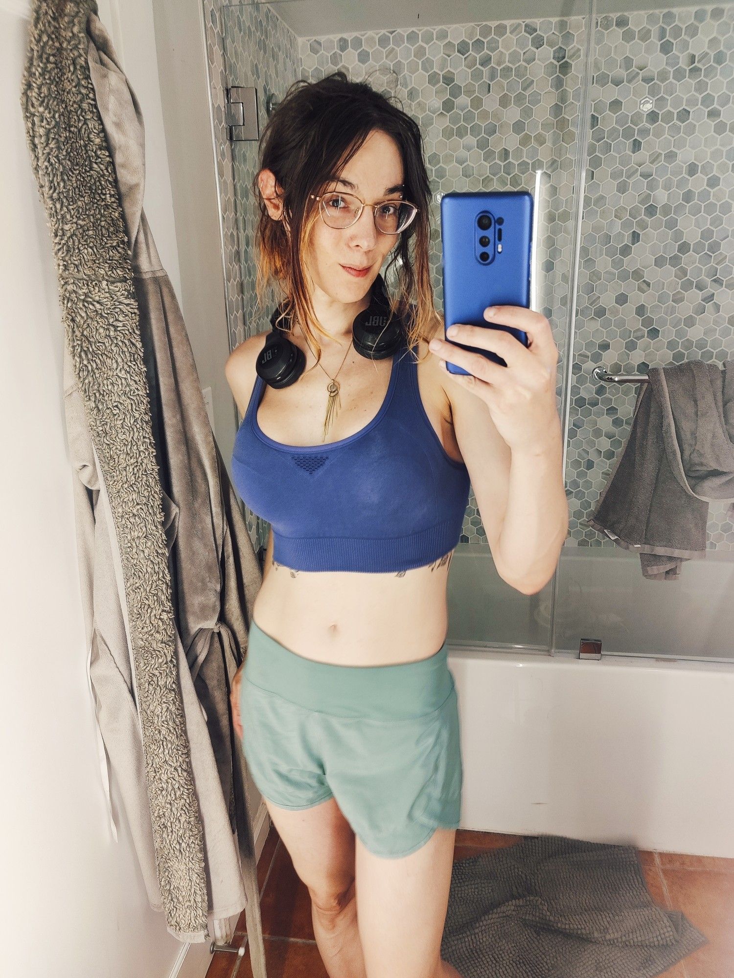 Cara taking a mirror selfie wearing a blue sports bra and green running pants 