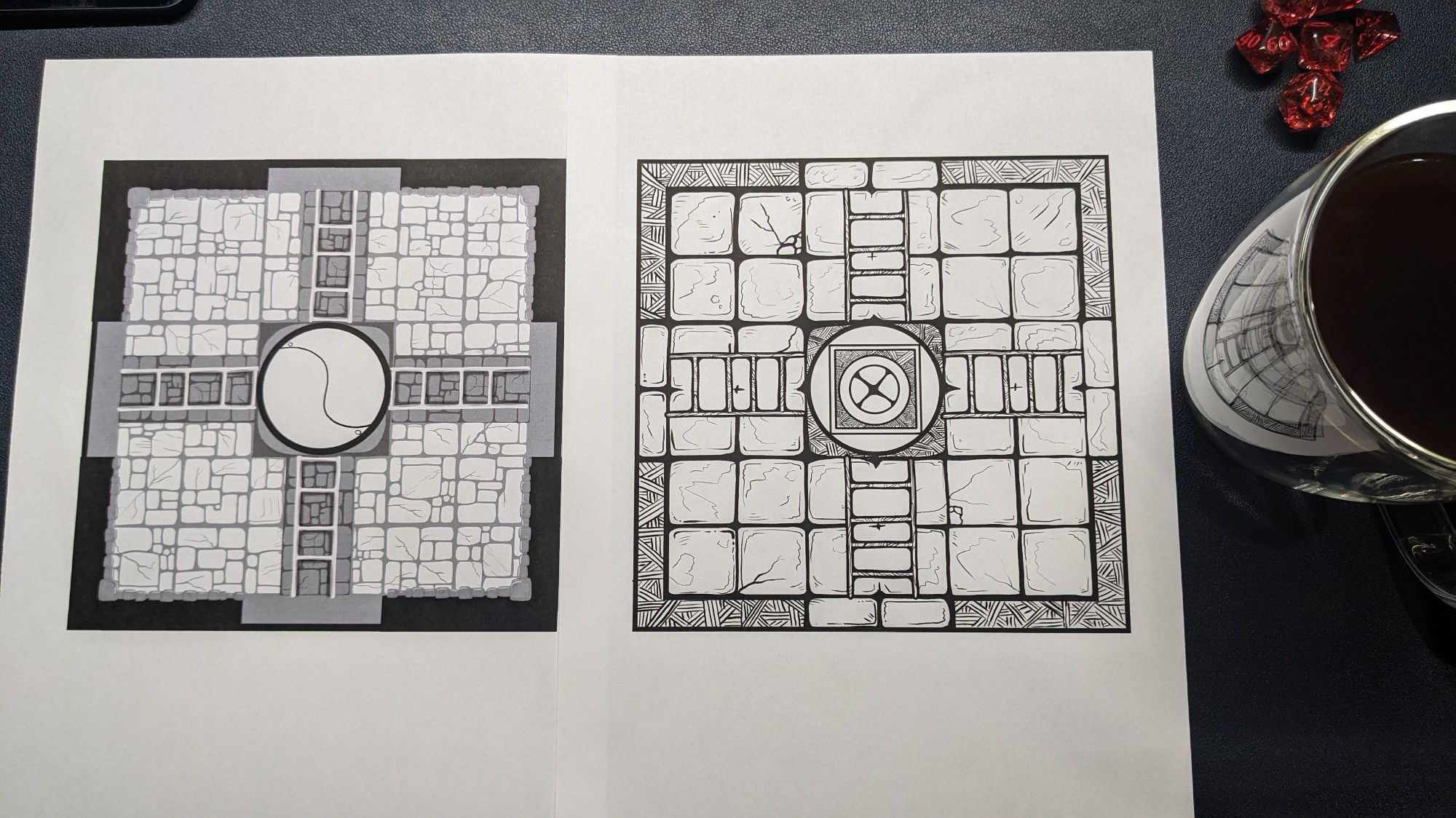 Two maps of similar rooms on a desk pad with coffee and dice