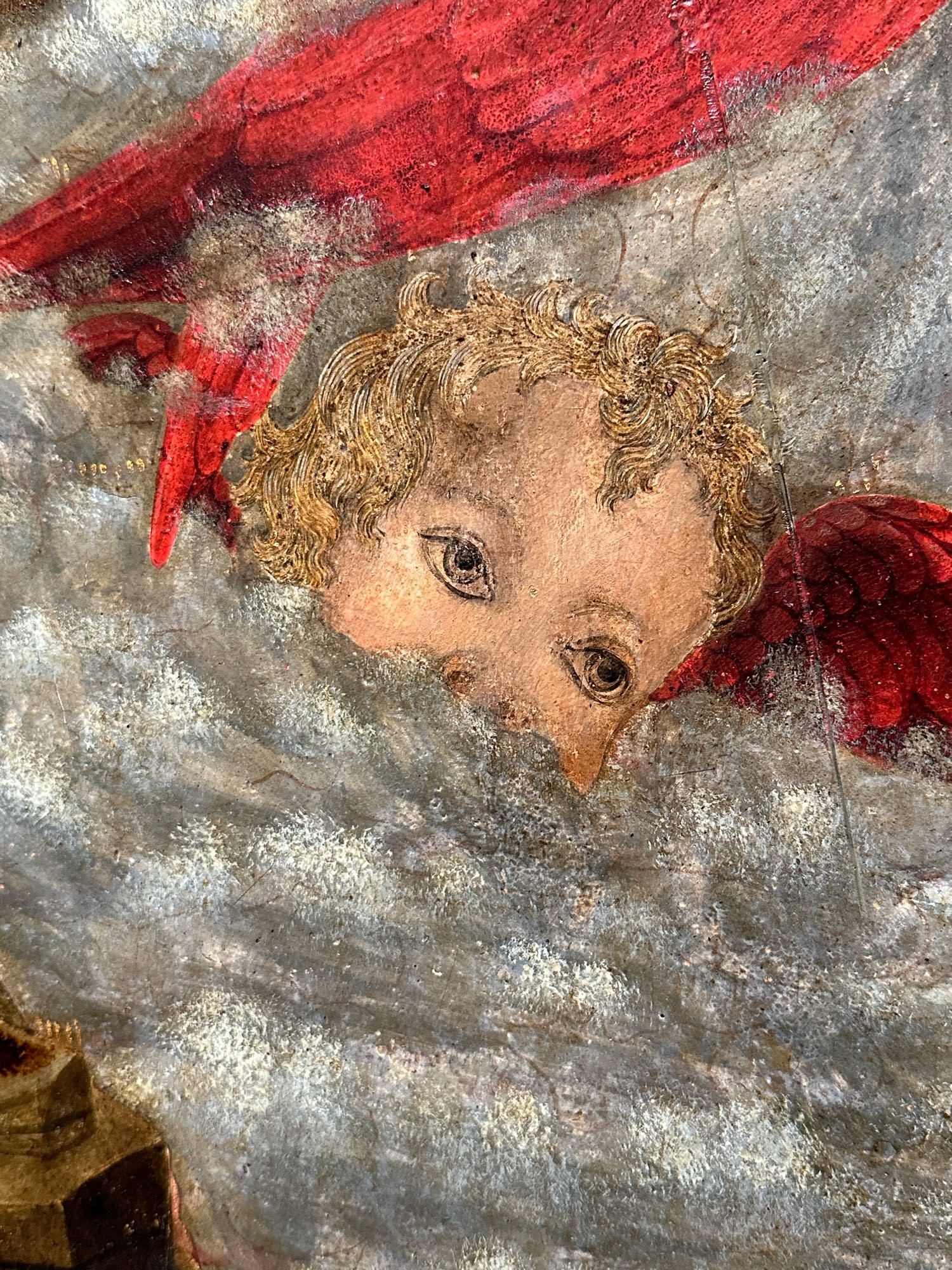 A painting of a cherub who is being cheeky and peeping over a cloud. 