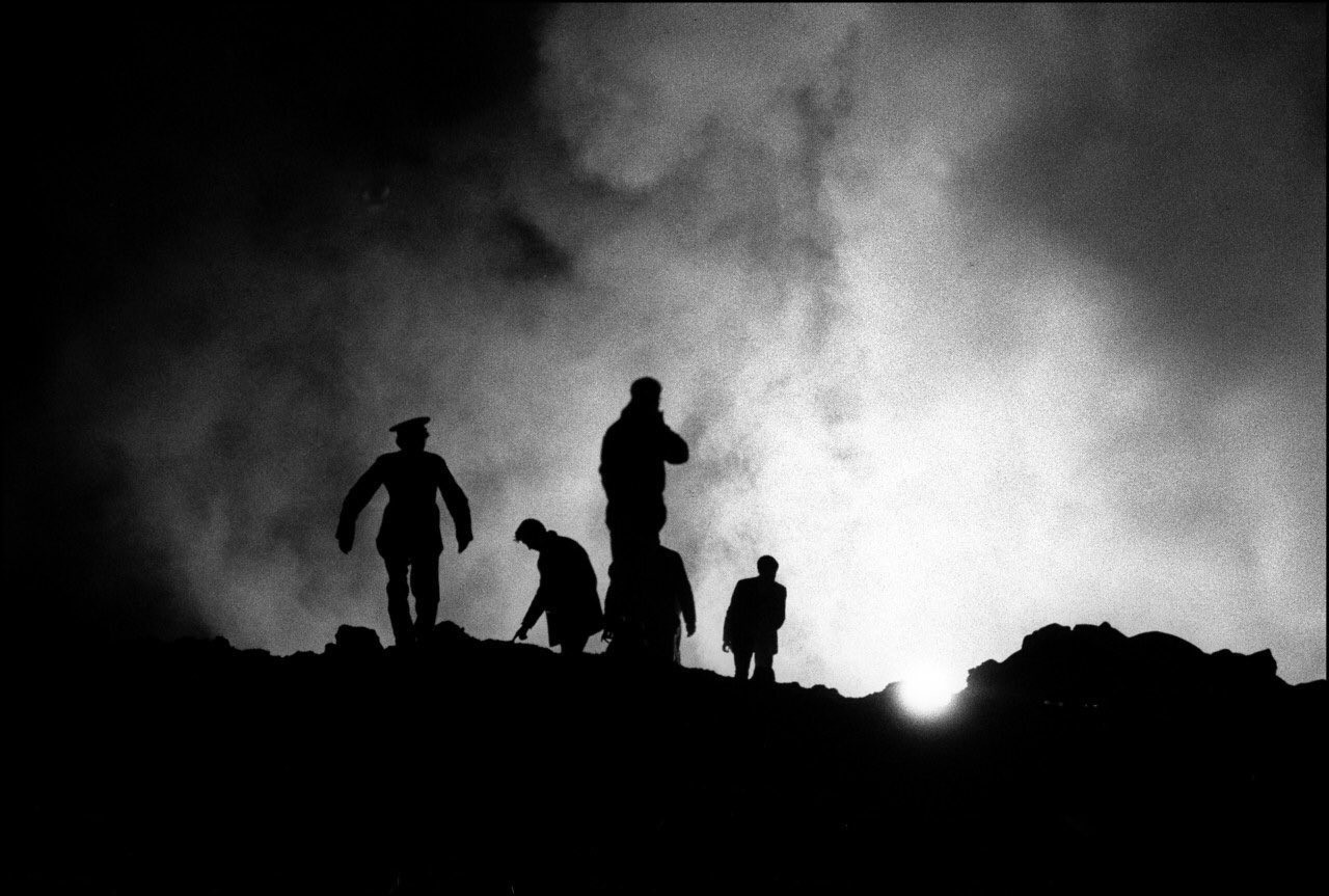 Police silhouetted against a night sky lit from behind 