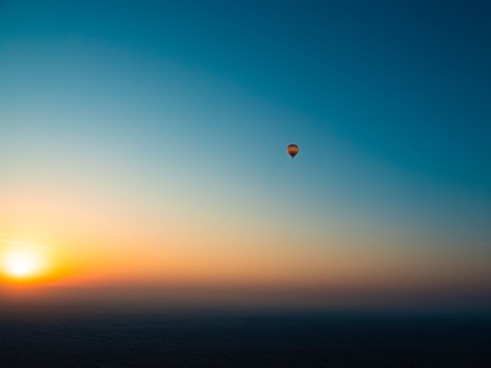 A photo of a hot air balloon during sunrise on a cloudless sky