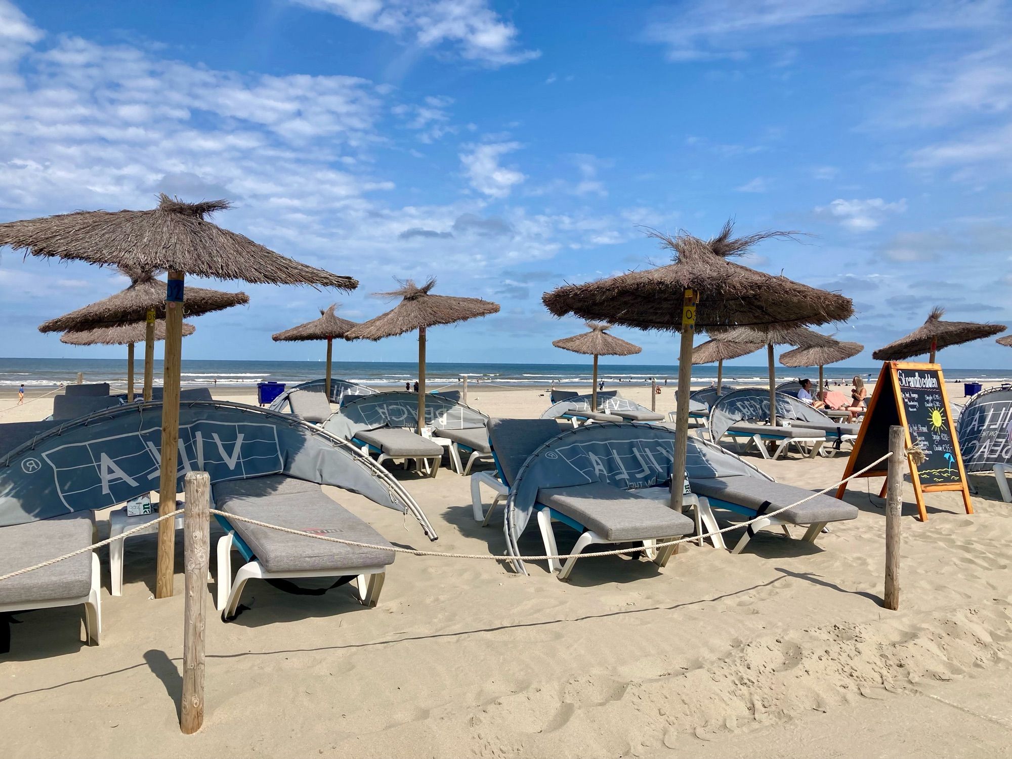 De ligbedden van de restaurants aan het lange pad langs het strand.