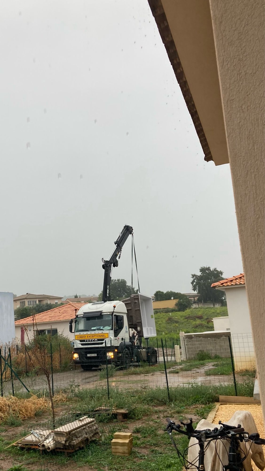 De vrachtwagen is bij de buurman gearriveerd met het zwembad achteruit gereden.