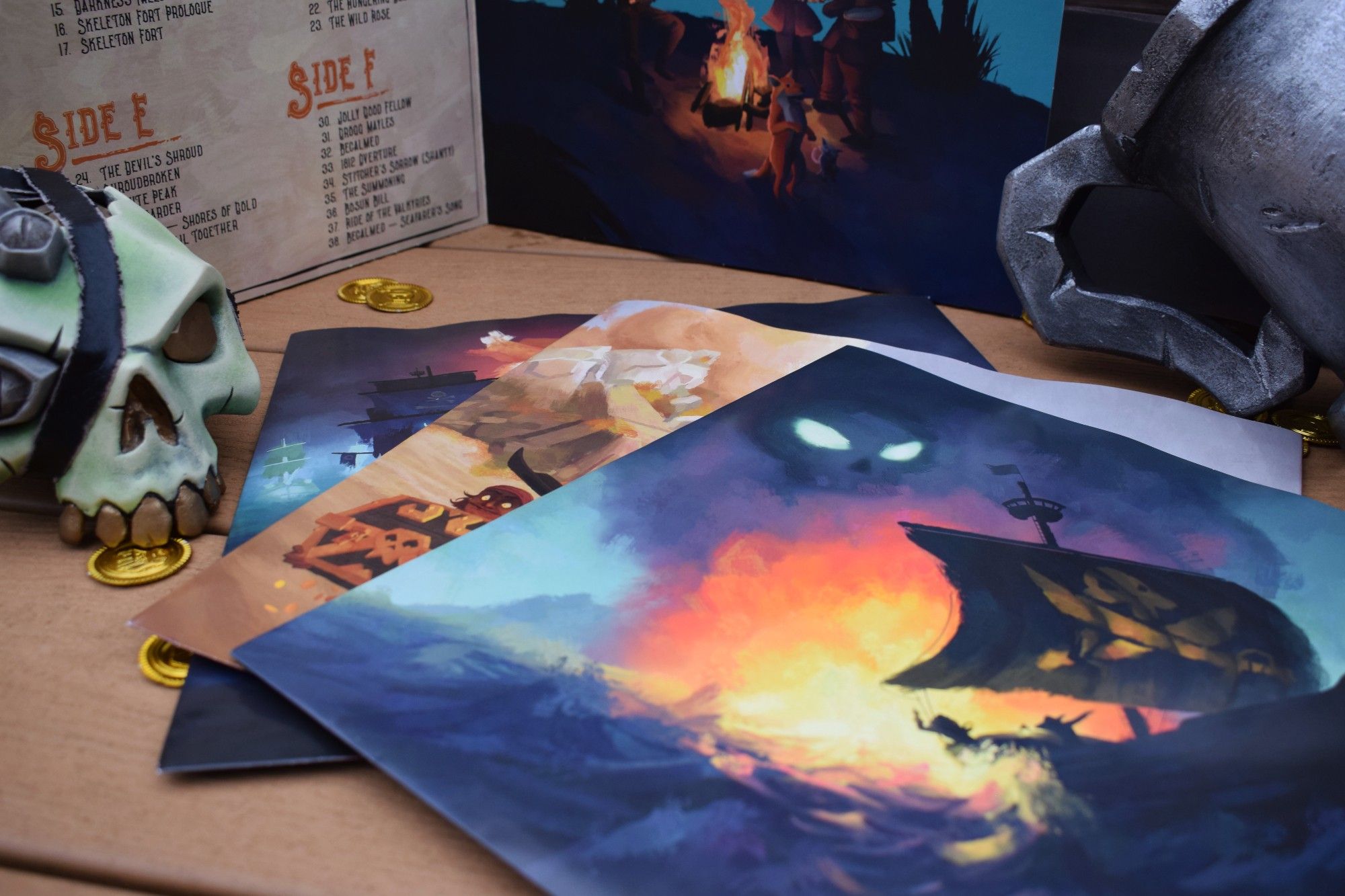 Three sleeves from the Sea of Thieves Vinyl Soundtrack all seen featuring stunning artwork. The most visible depicts a ship sailing away from a large explosion.