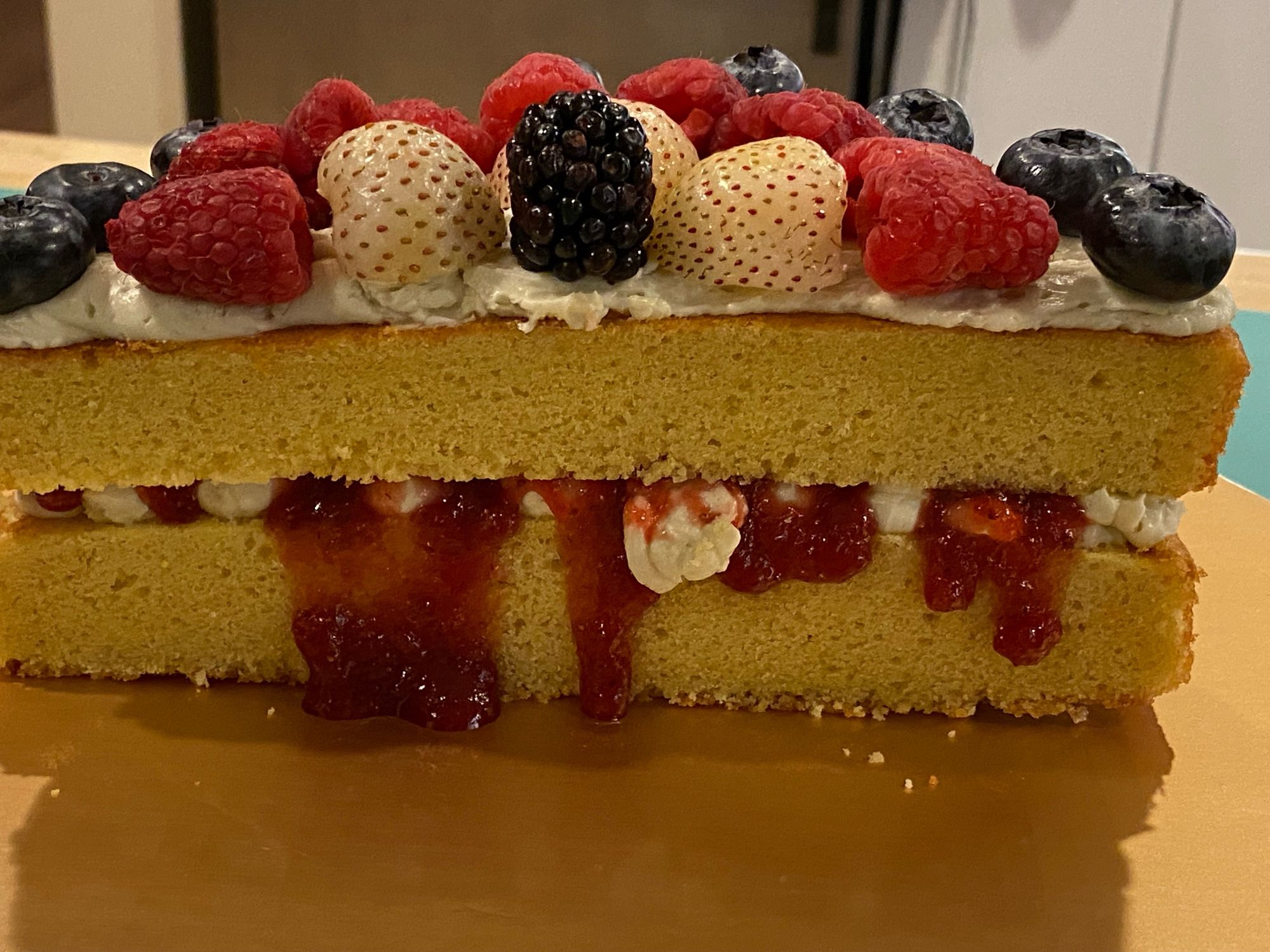 Crossection of a homemade Victoria Cake, topped with fruit.