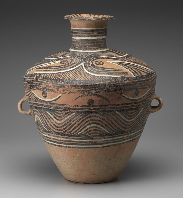 large vessel with pair of lug handles; small flat foot, flaring outward to pointed shoulder; straight neck with outward-flaring rim; swirl, linear and crosshatch painted designs in black and white
Located in the far northwest of China, the Majiayao culture (c. 3800-2000 b.c.) produced an accomplished painted pottery tradition. Although originally derived from the Yangshao culture, Majiayao is now considered a culture of its own. Many of its tomb sites in Qinghai and Gansu provinces were richly furnished with decorative pottery. The culture went through an evolution of painted pottery designs that lasted more than a thousand years. During the Majiayao phase (3100-2700 b.c.), when this spectacular storage jar was created, painted decoration had become independent. Designs have a distinctive linear quality with black parallel lines encircling the vessel with fluid and rhythmic movements creating striking graphic effects. The additional use of a white pigment, here effectively used to highlight the design, is somewhat rare. The vessel comes from Gansu or Qinghai province in the upper Huang Ro (Yellow River) basin; probably the most prolific pottery producing area between 4000 and 2000 b.c. The Majiayao region would later produce two other distinct types of painted pottery; Panshan (2600-2300 b.c.) and Mazhang (1200-2000 b.c.), classic examples of which are displayed below and to the left.