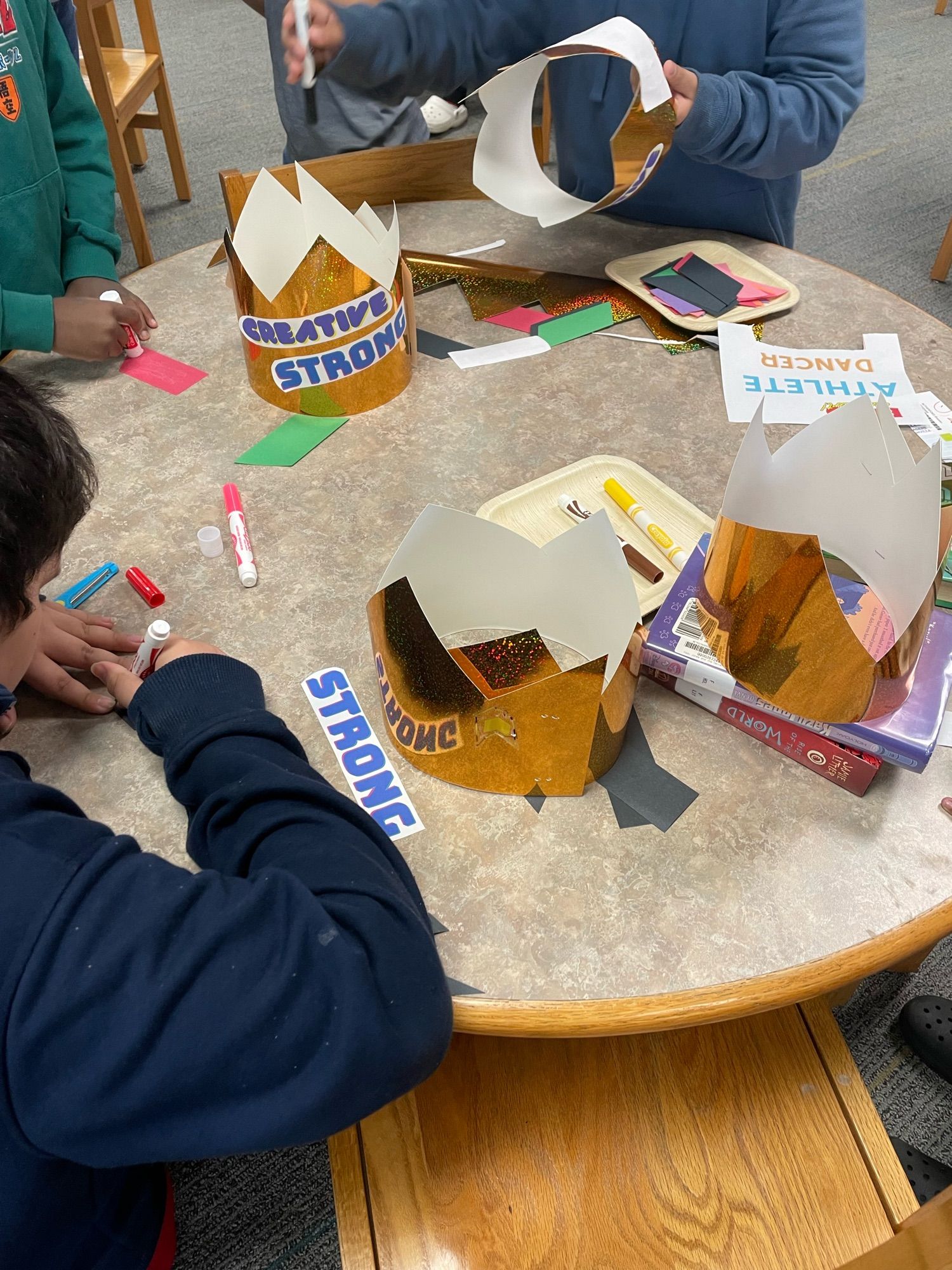 Young kids standing around a table making crowns out of words