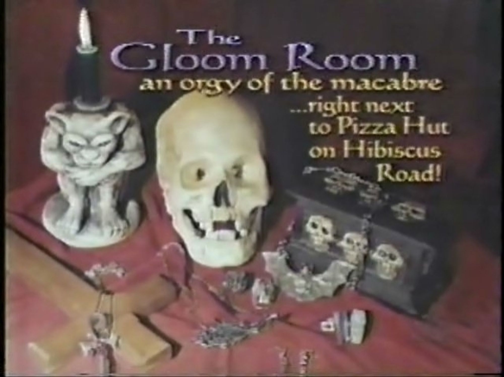 It's a still from a TV show, low resolution. It features a fake skull some spooky jewelry an upside down cross and a gargoyle candle holder it reads "The Gloom Room an orgy of the macabre ....  right next to the pizza hut on Hibiscus road!" Happy Halloween